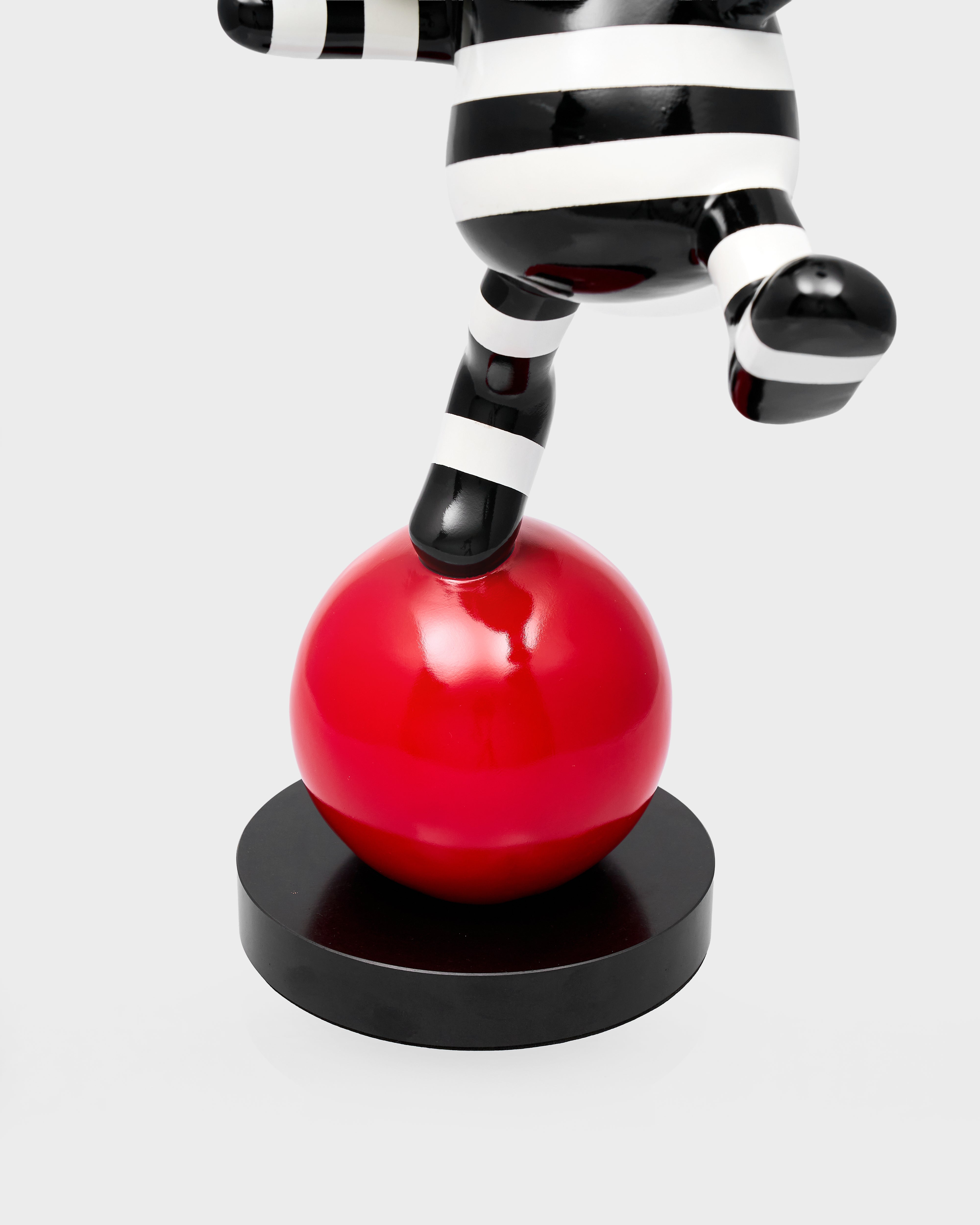 Black and white striped leg on a red ball with a white background