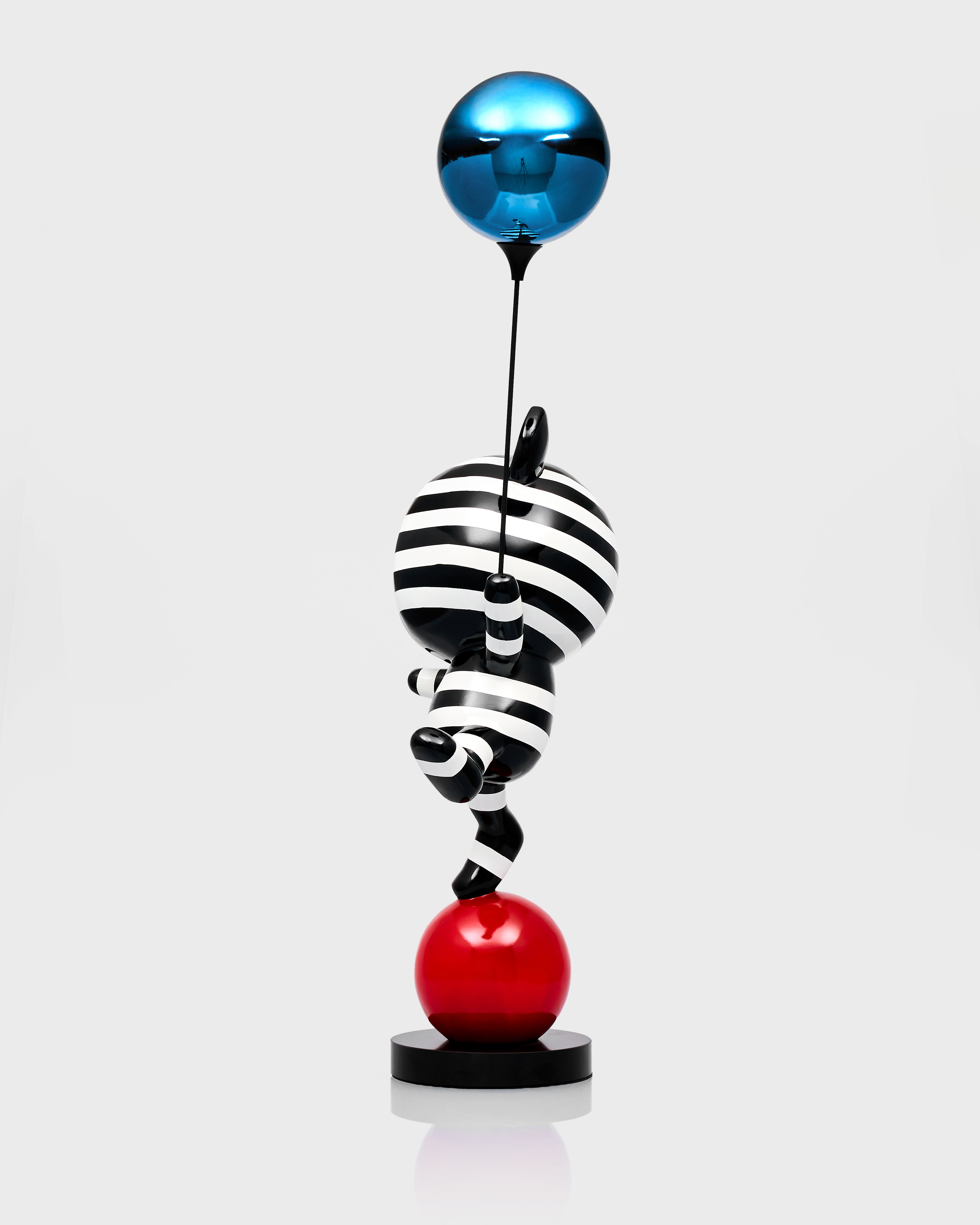 Abstract sculpture with striped ball and blue sphere on a white background