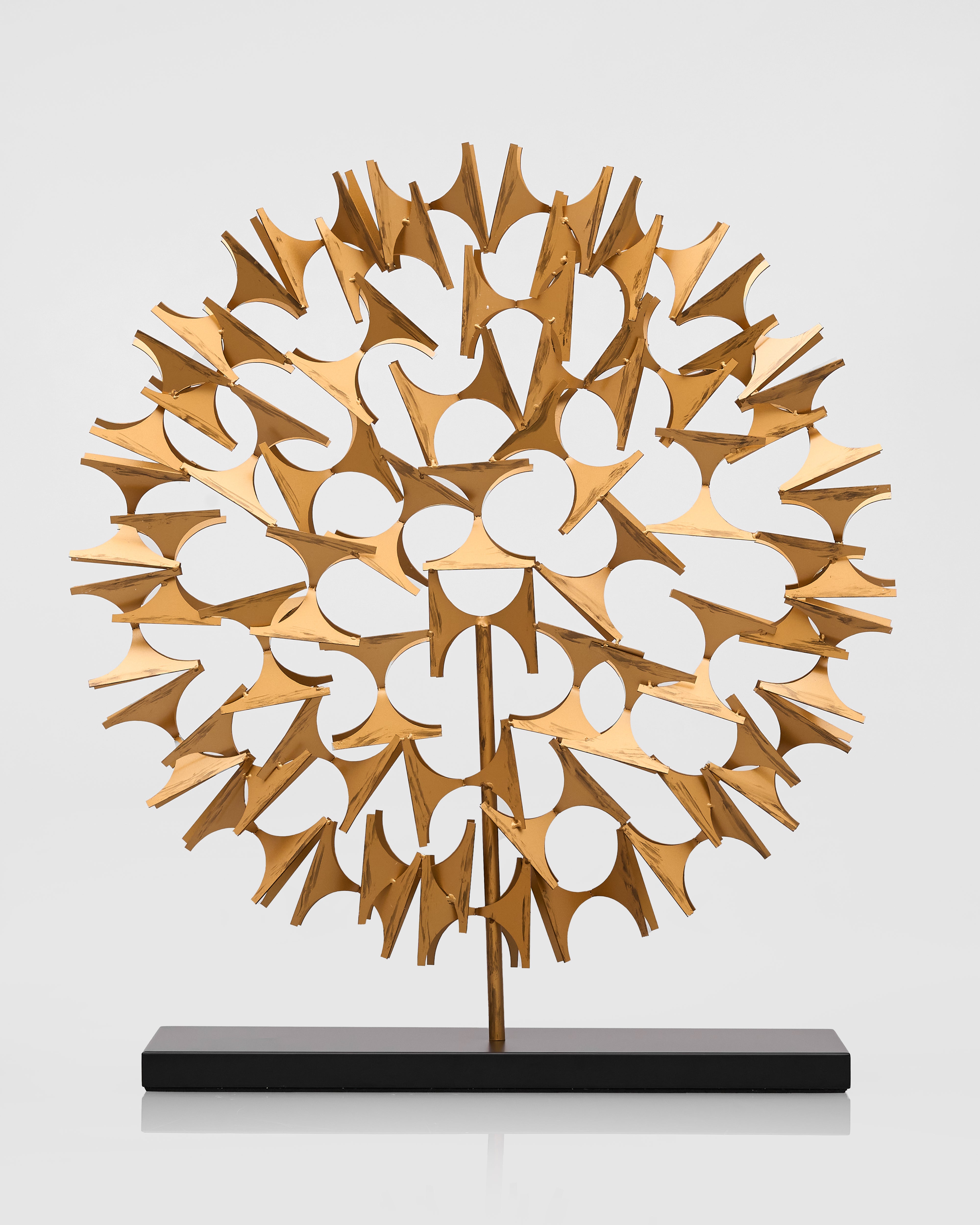 Gold and white abstract sculpture on a black base against a light gray background