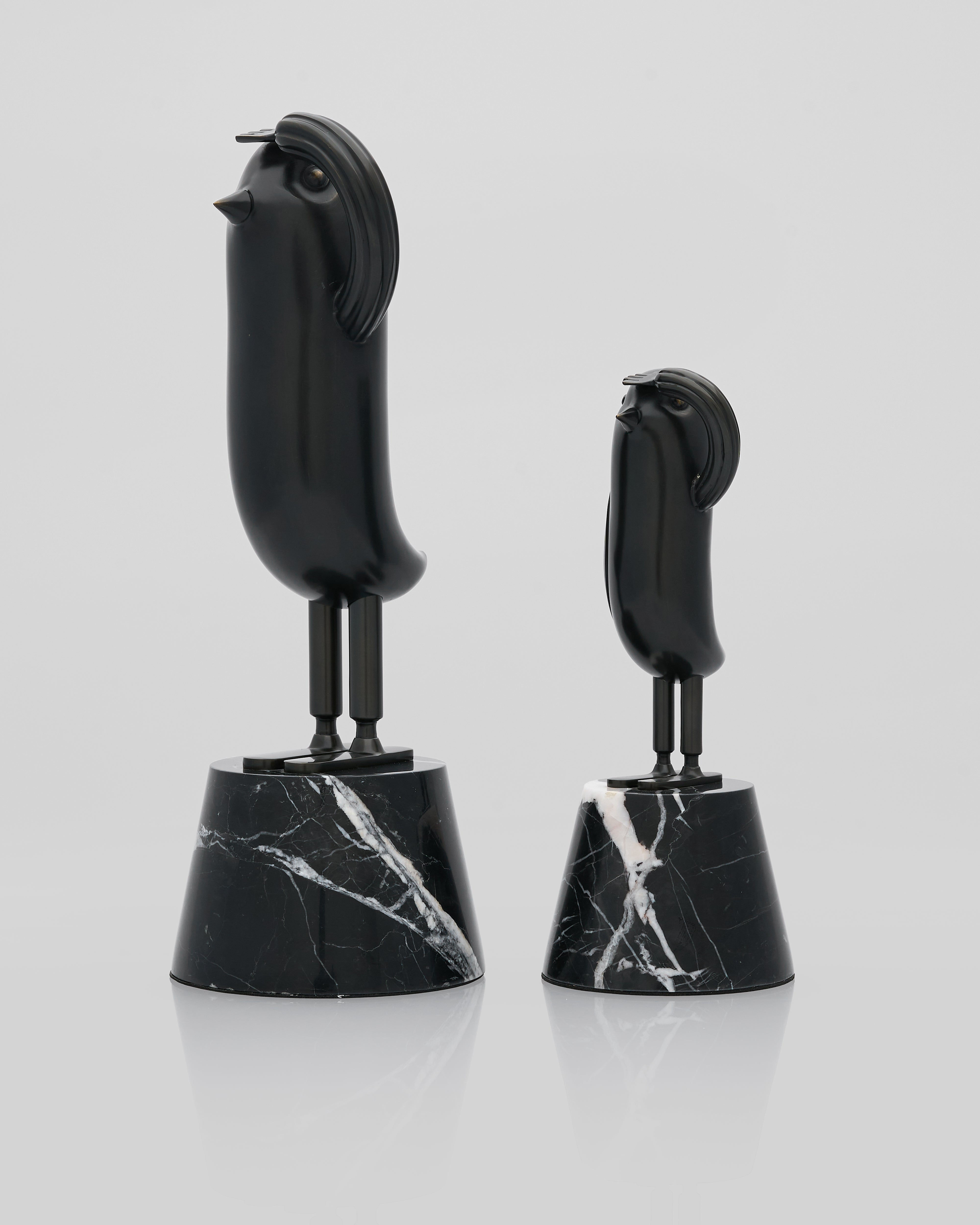 Two black marble salute figurine bird -shaped objects on a light gray background
