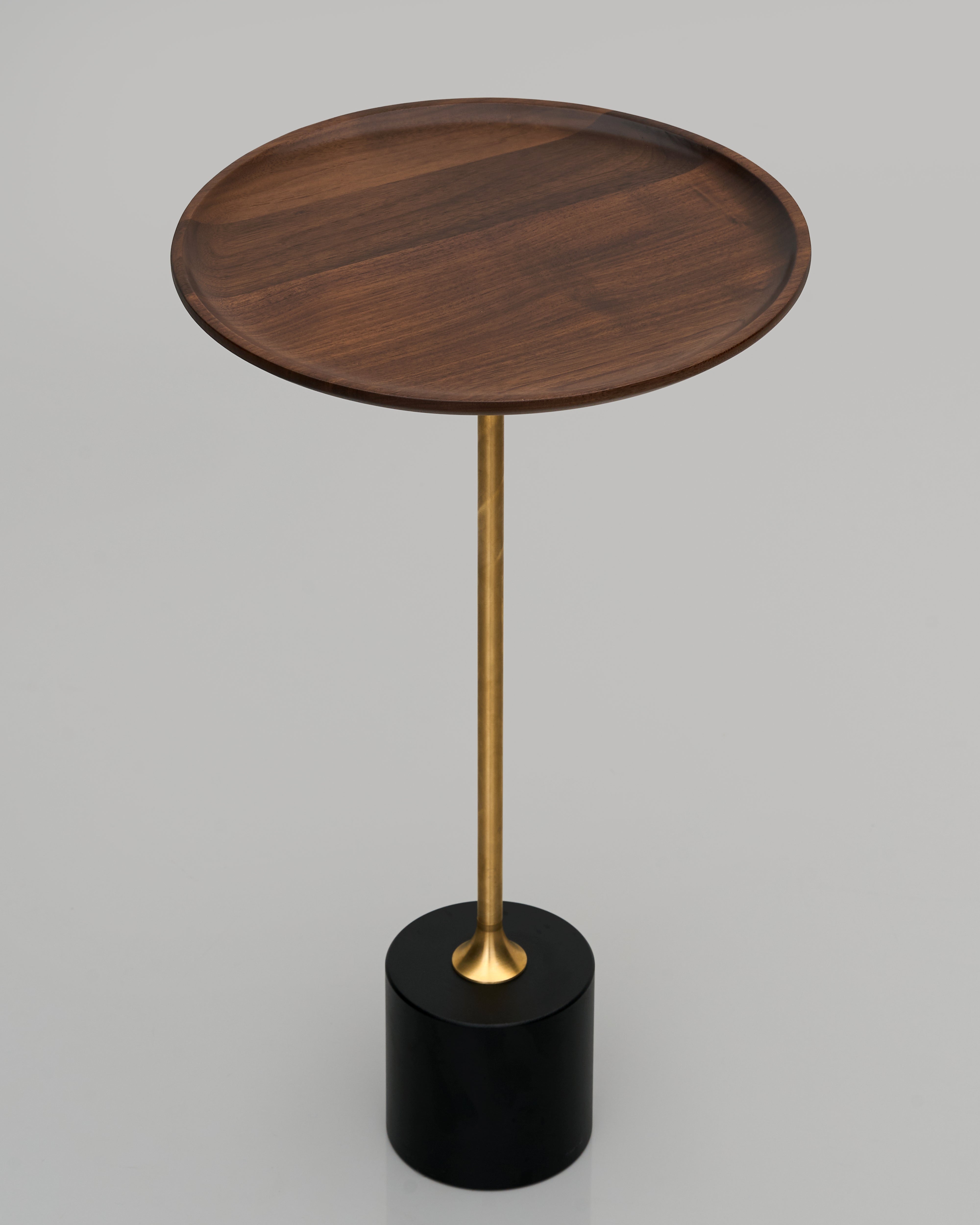 Wooden side table with brass leg and black base on a gray background
