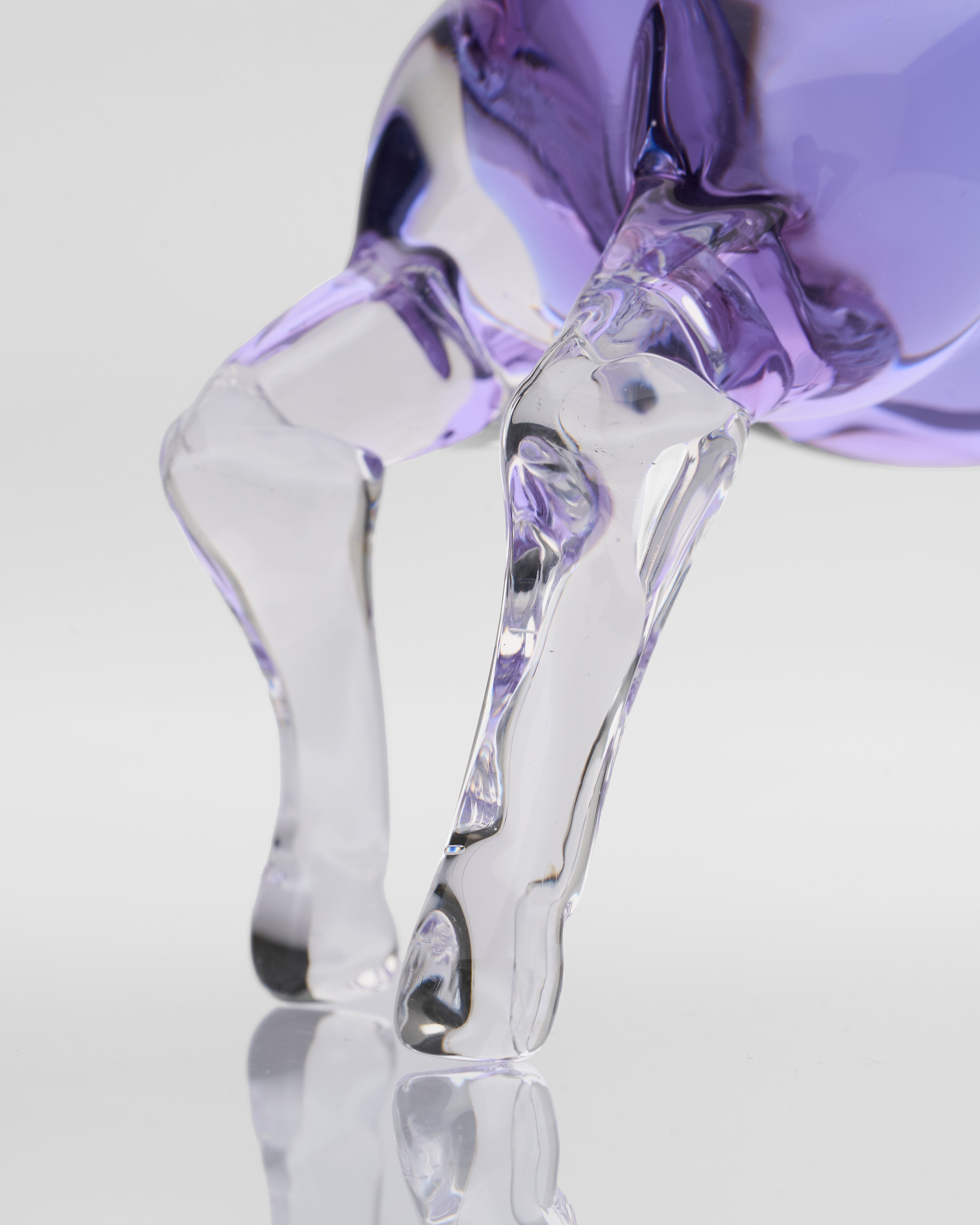 Clear glass sculpture on a reflective surface with a purple horse legs