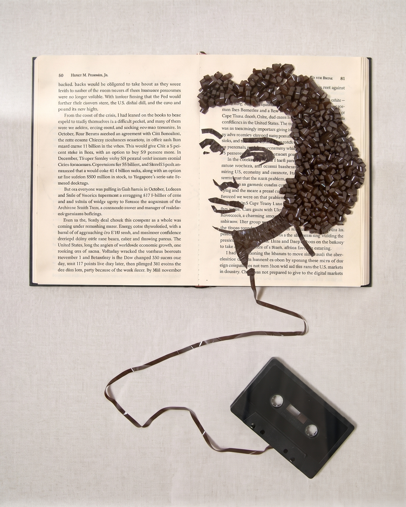 Artistic arrangement with an open book, face drawing, and cassette tape inside a clear frame.