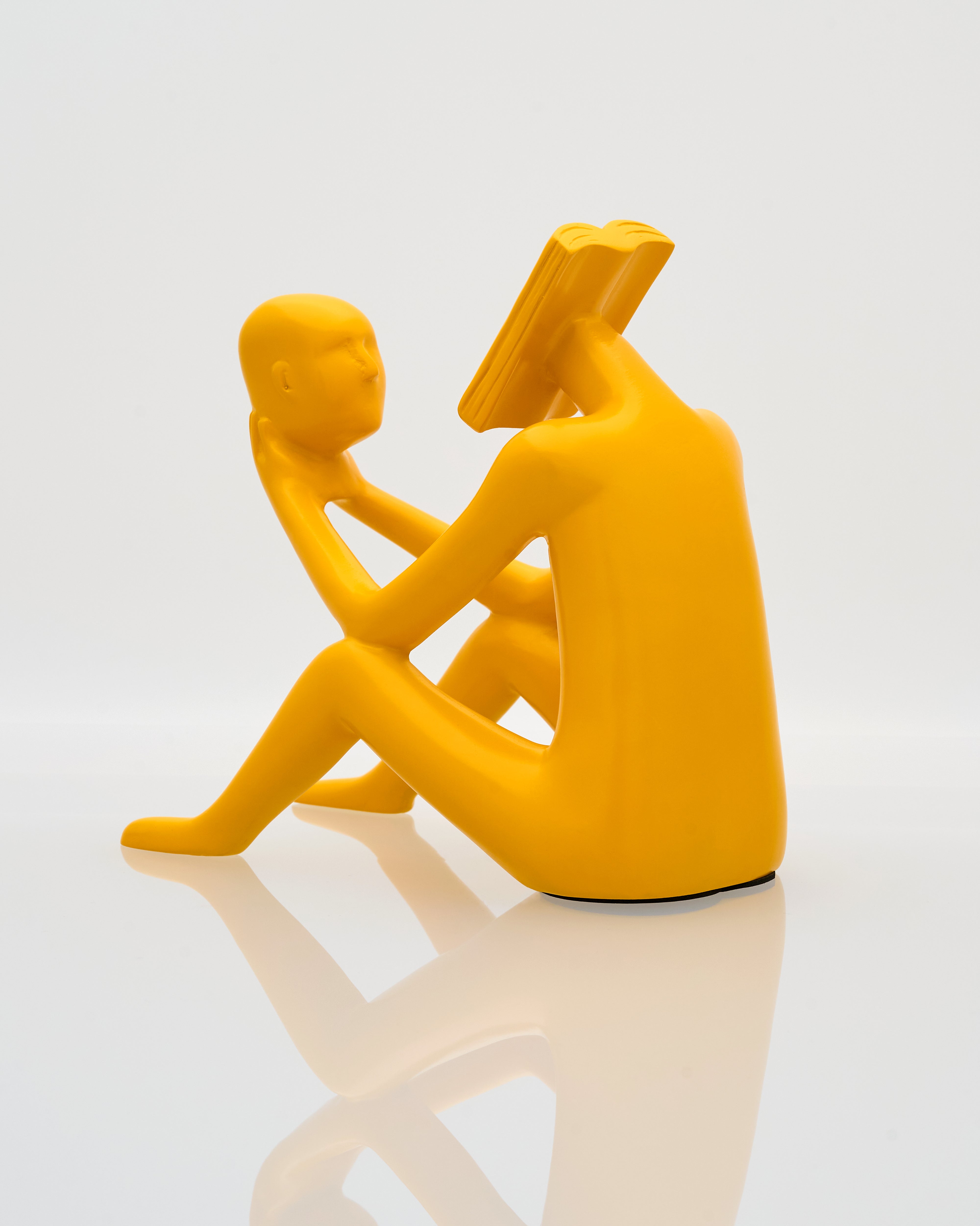 Yellow ceramic sculpture of two people embracing on a white background