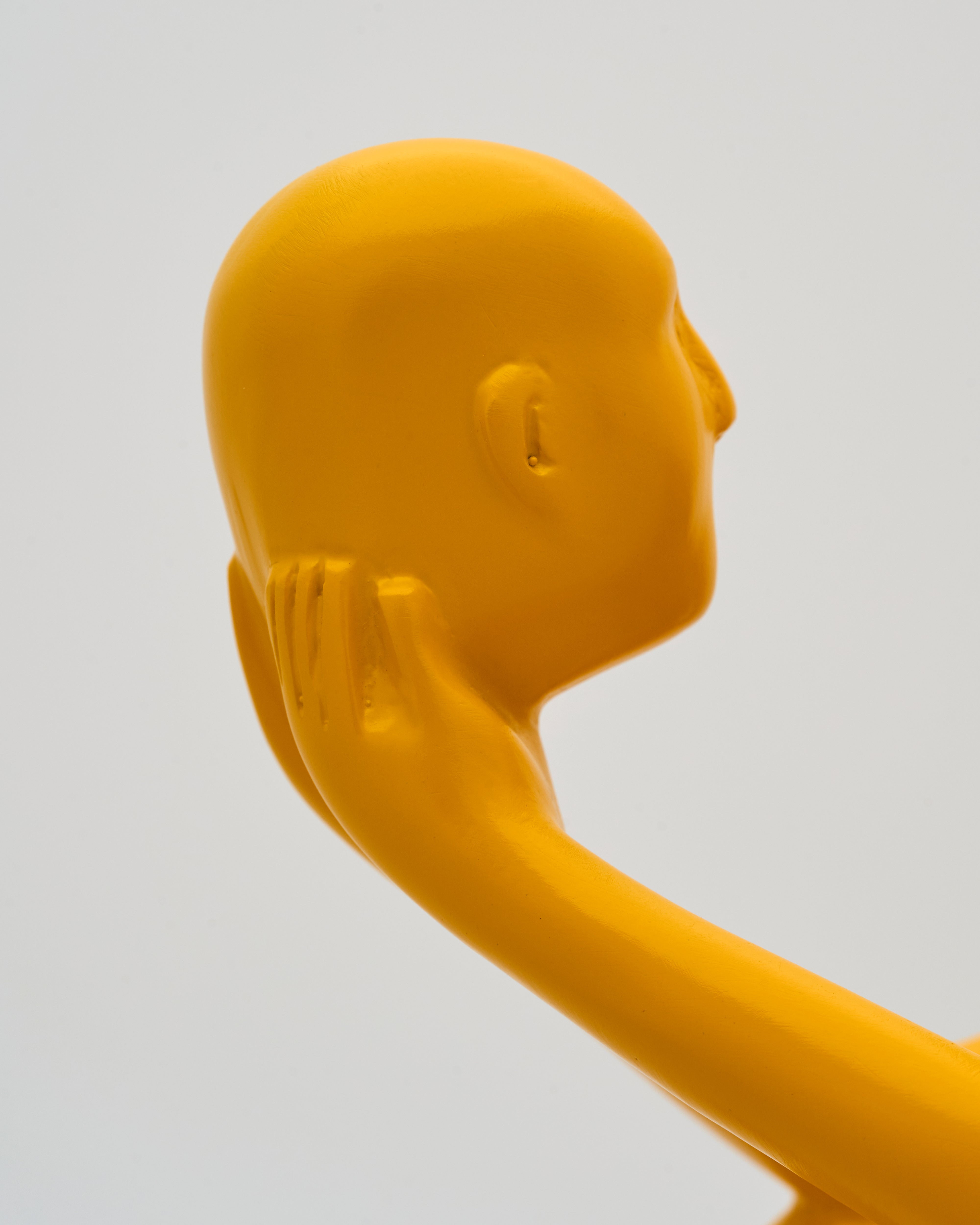 Yellow rubber duck with a hand on its face against a light gray background