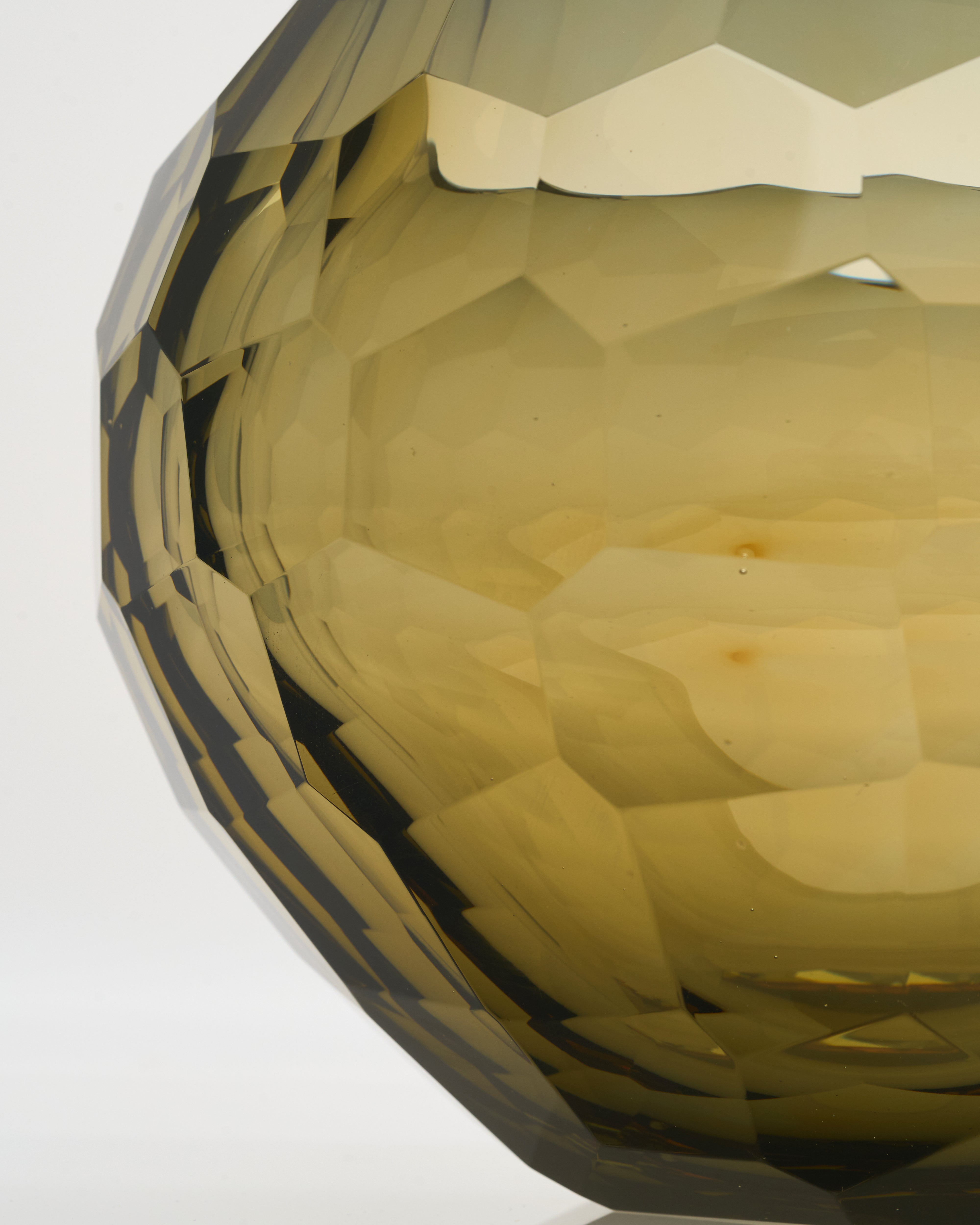 Close-up of a geometric, faceted object with a reflective surface on a white background