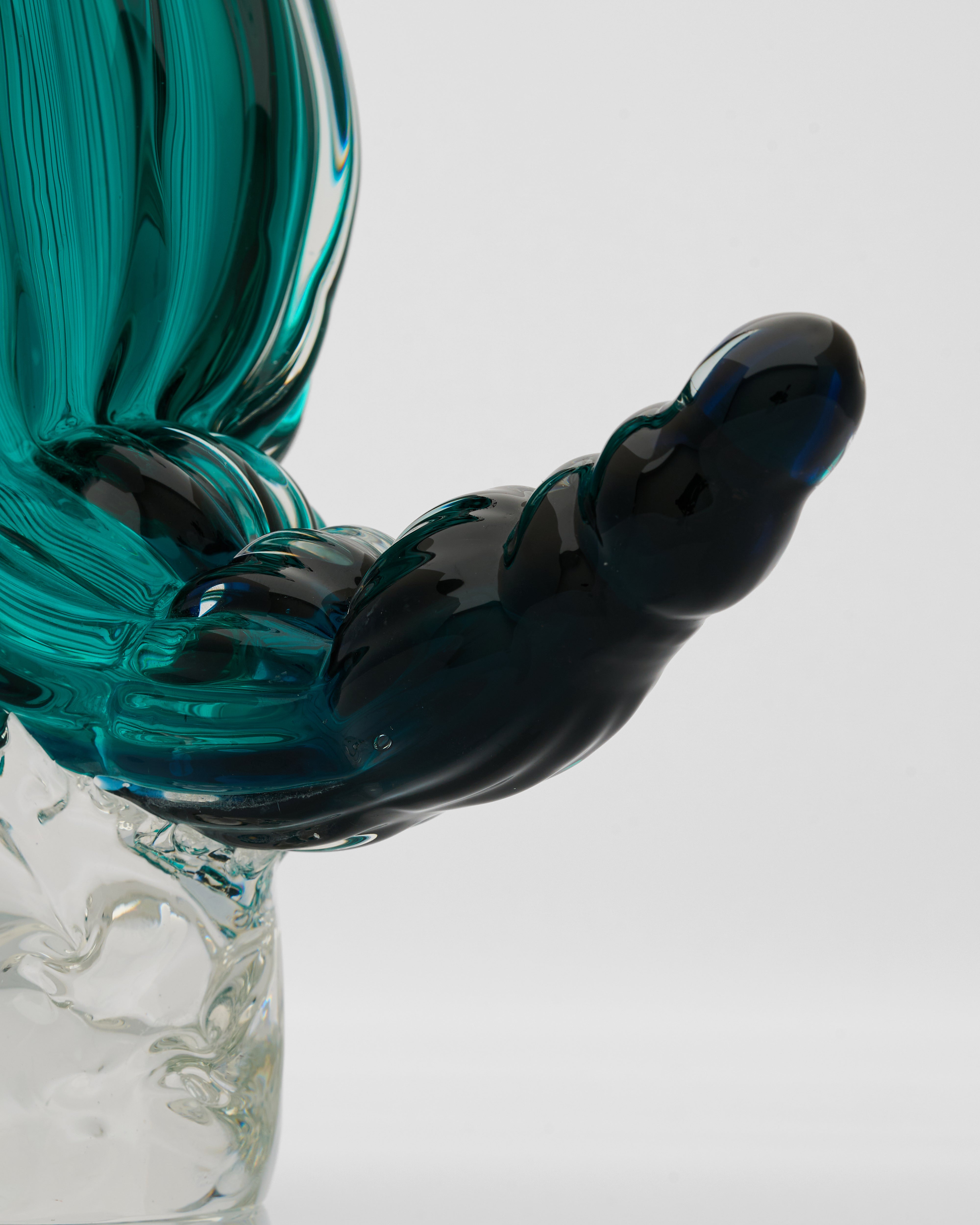 Glass sculpture with teal and black colors on a white background