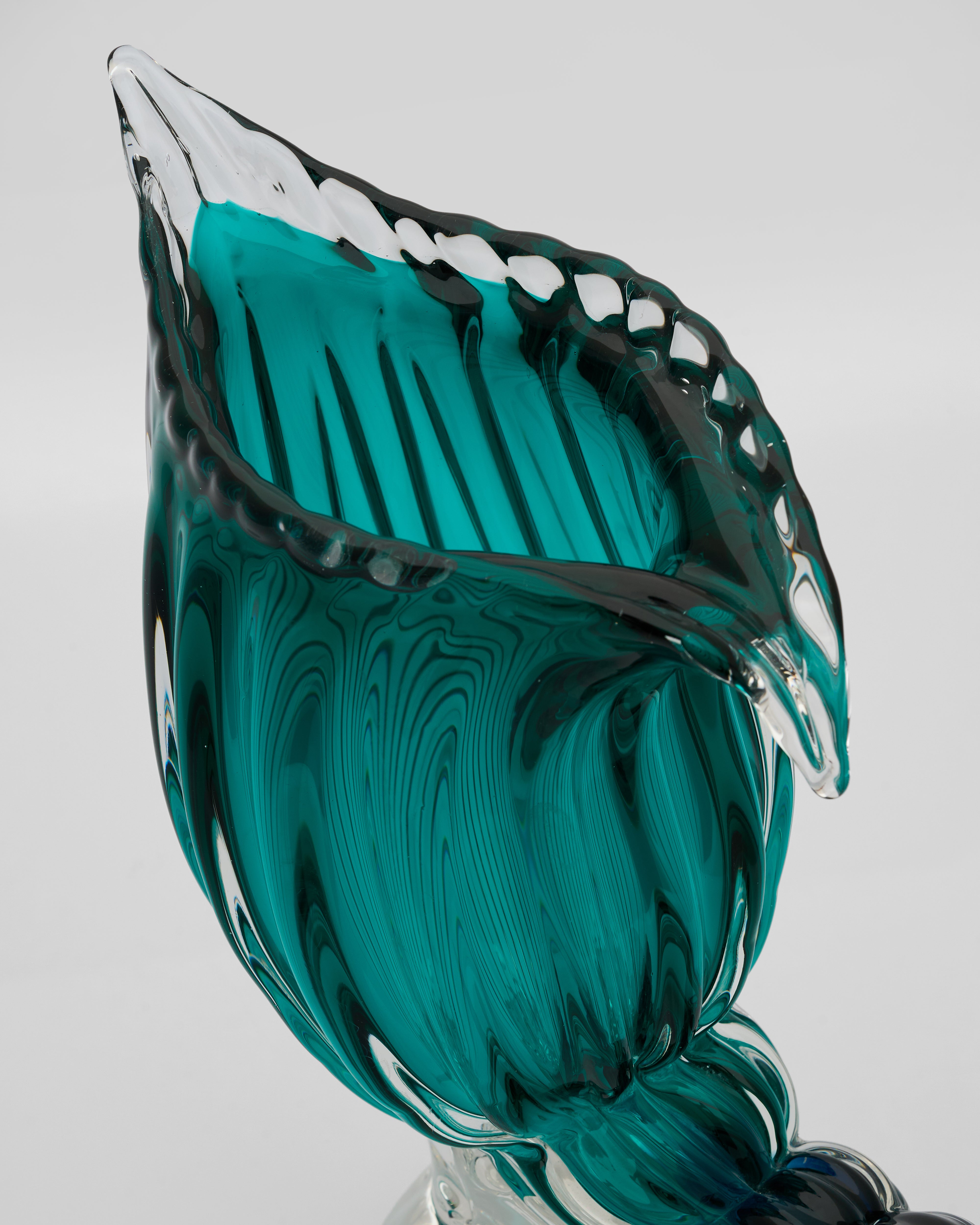 Teal glass sculpture with wavy design on a white background
