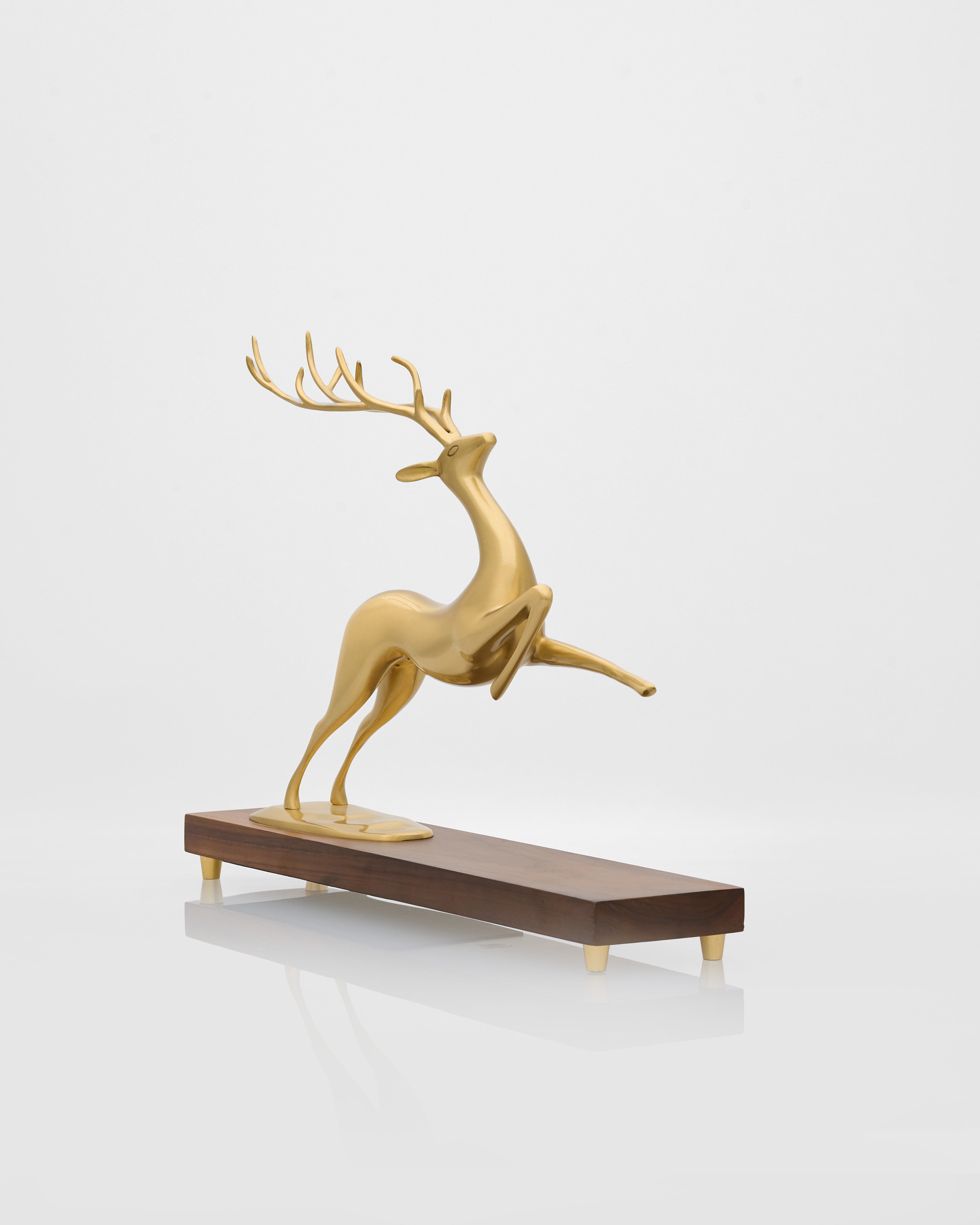 Gold deer figurine on a wooden base against a white background