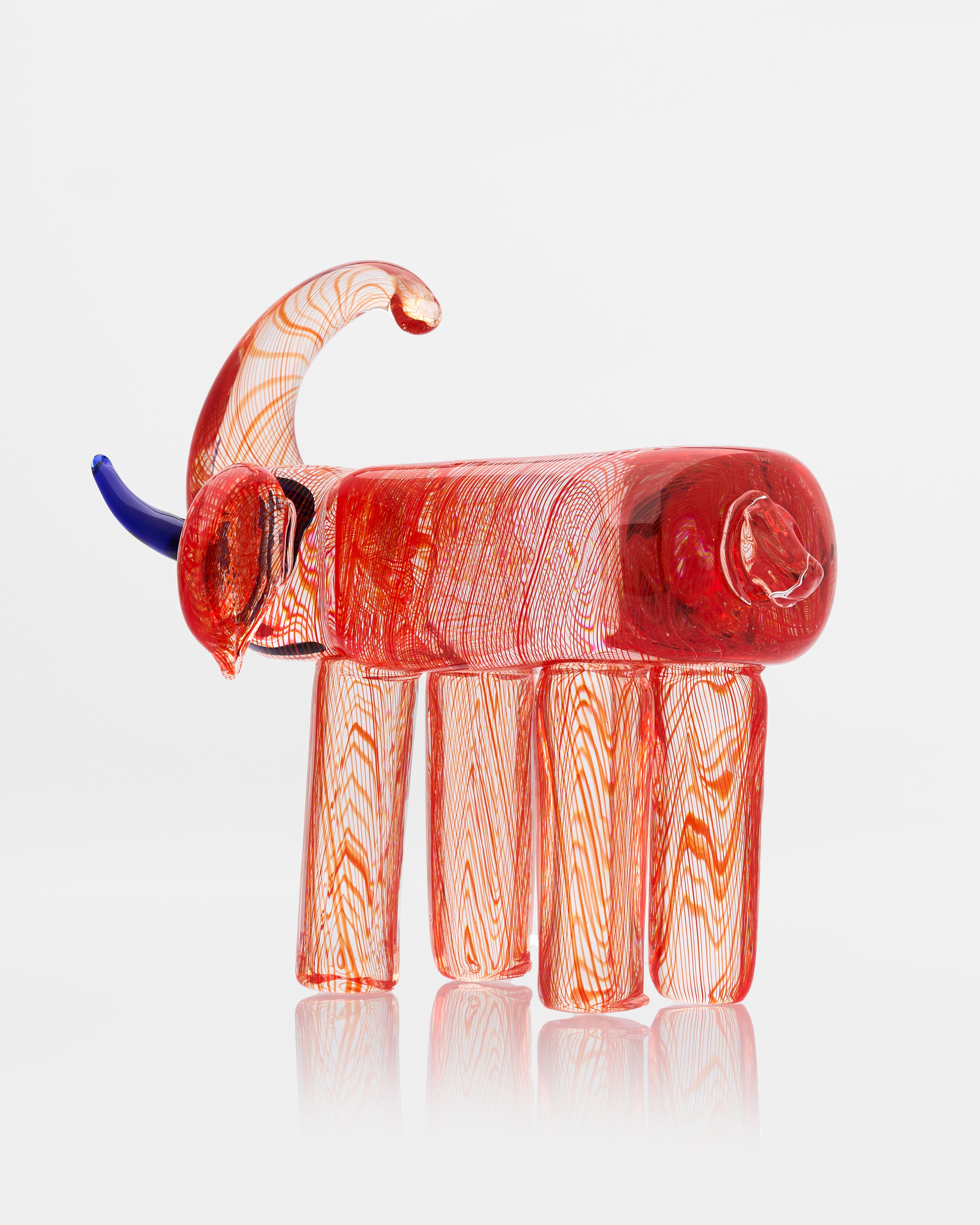 Glass elephant figurine with a red body and blue trunk on a white background