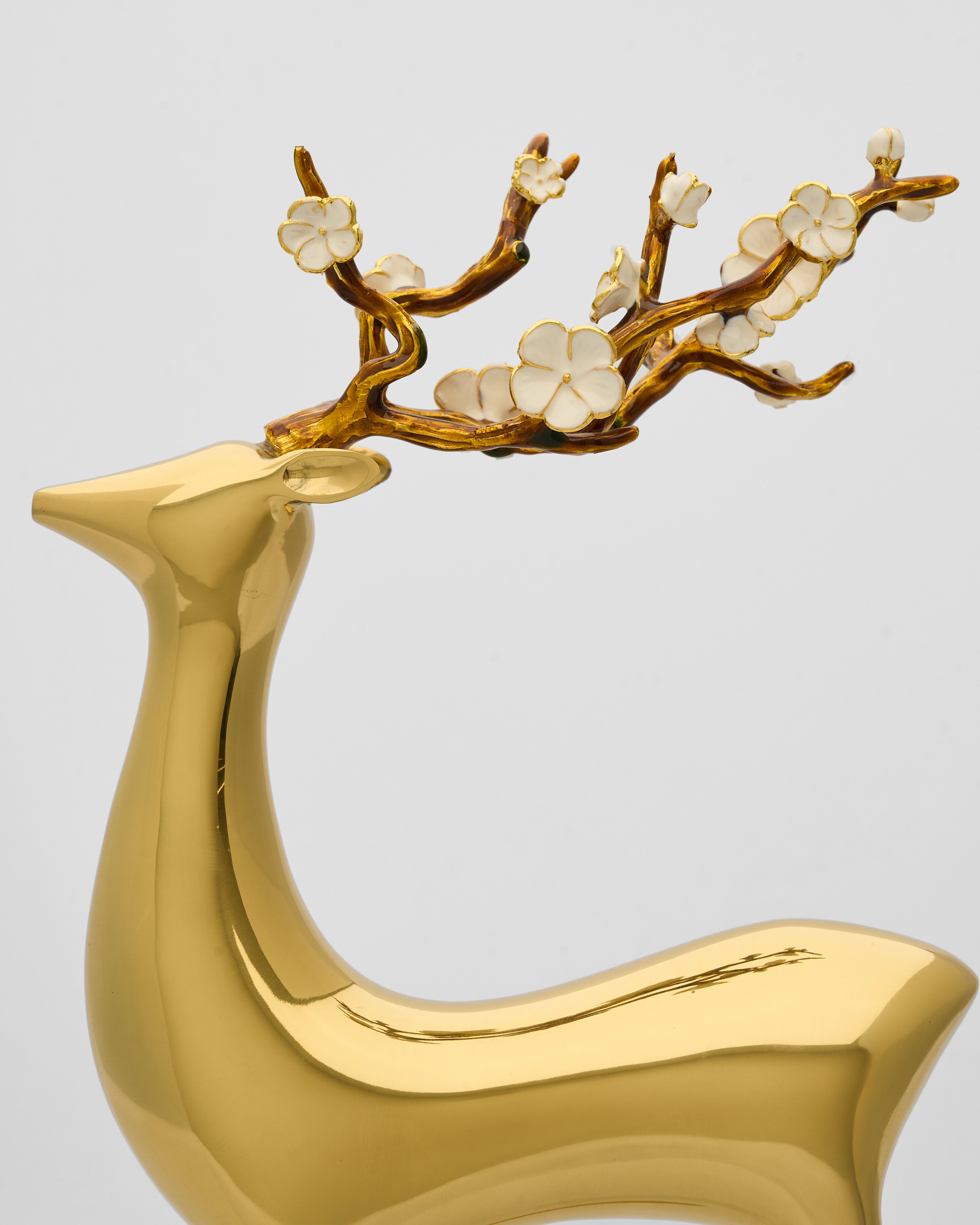 Gold deer figurine with floral antlers on a light gray background