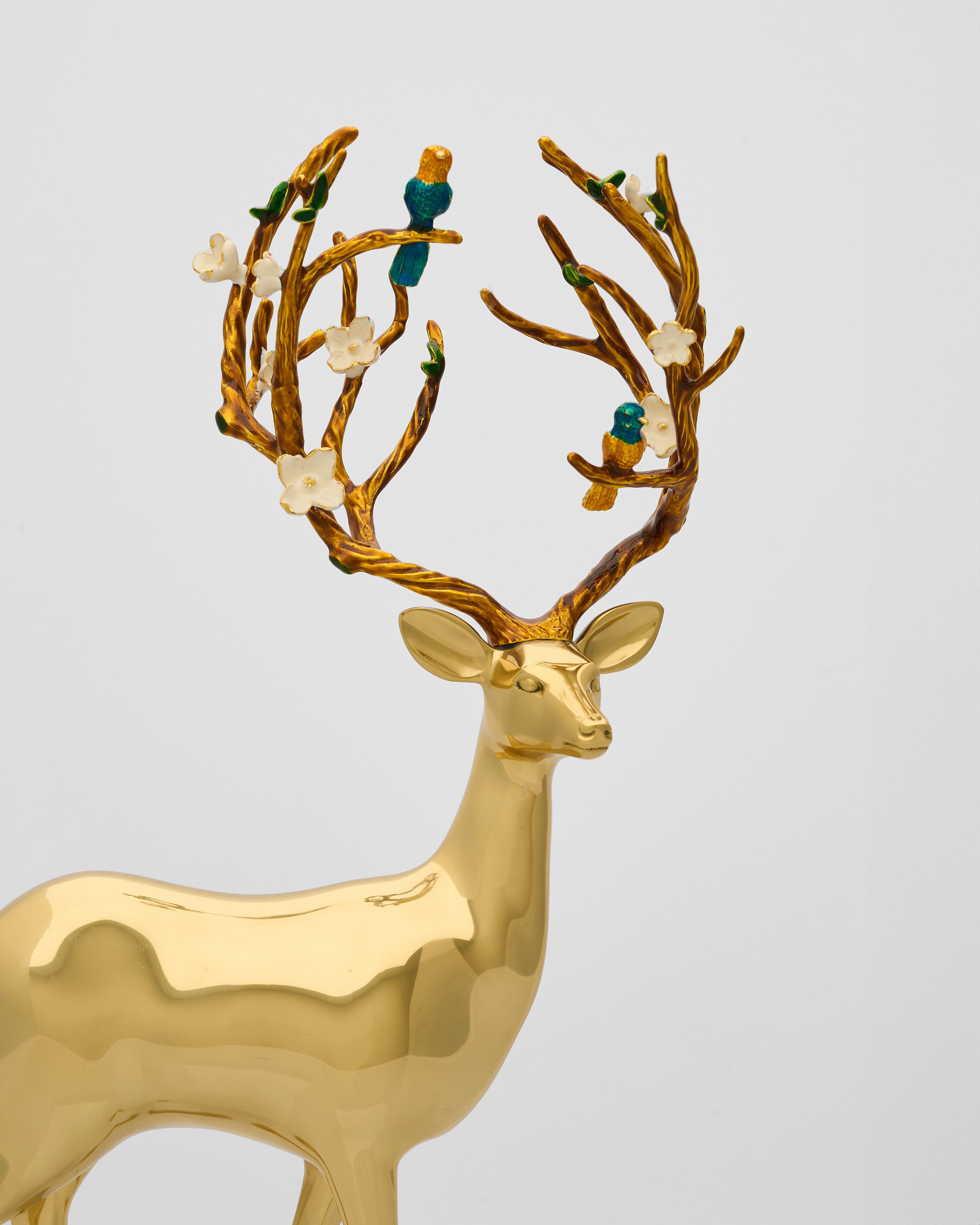 Gold deer figurine with decorative antlers on a light gray background