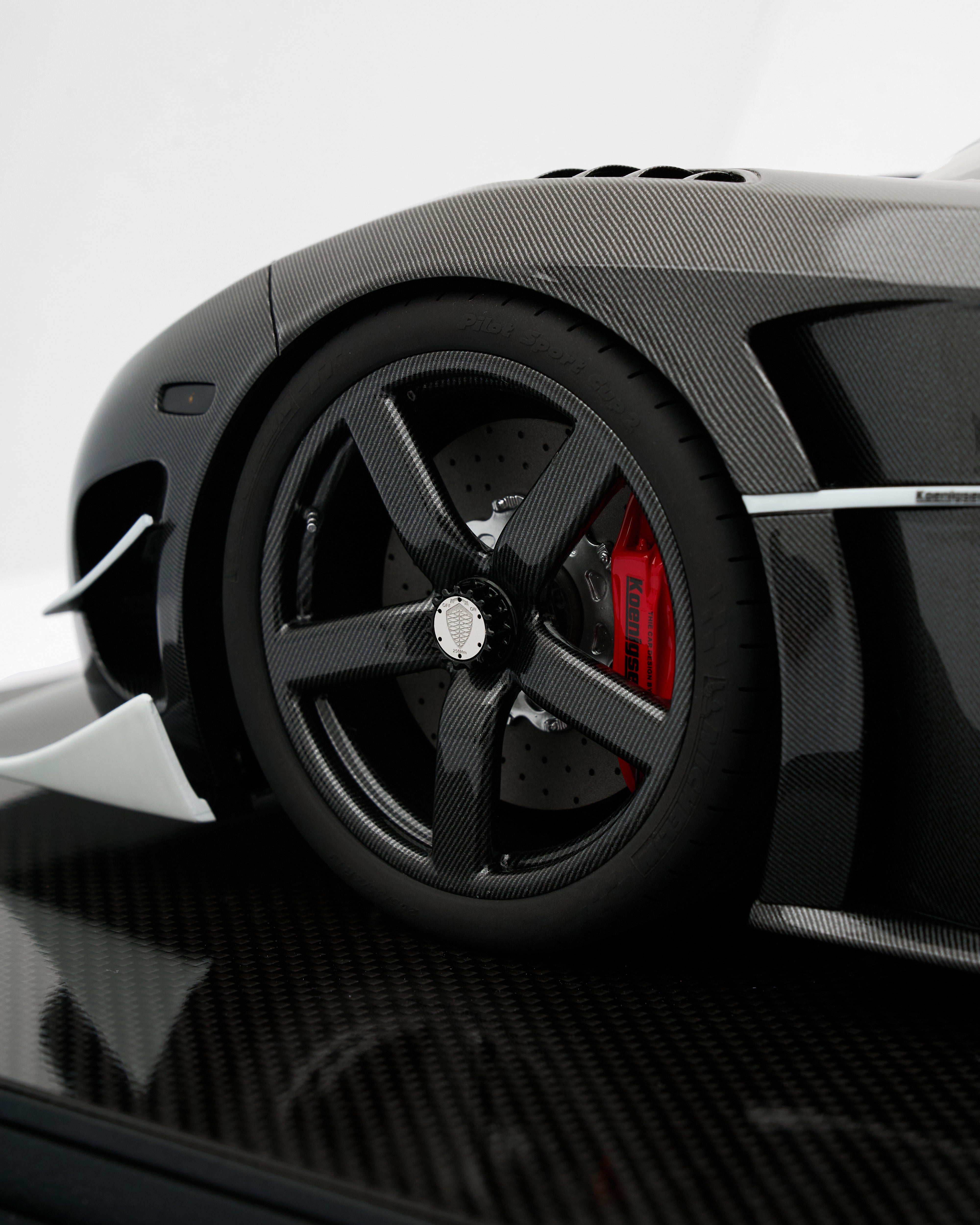 Close-up of a black sports car wheel with red accents on a white background