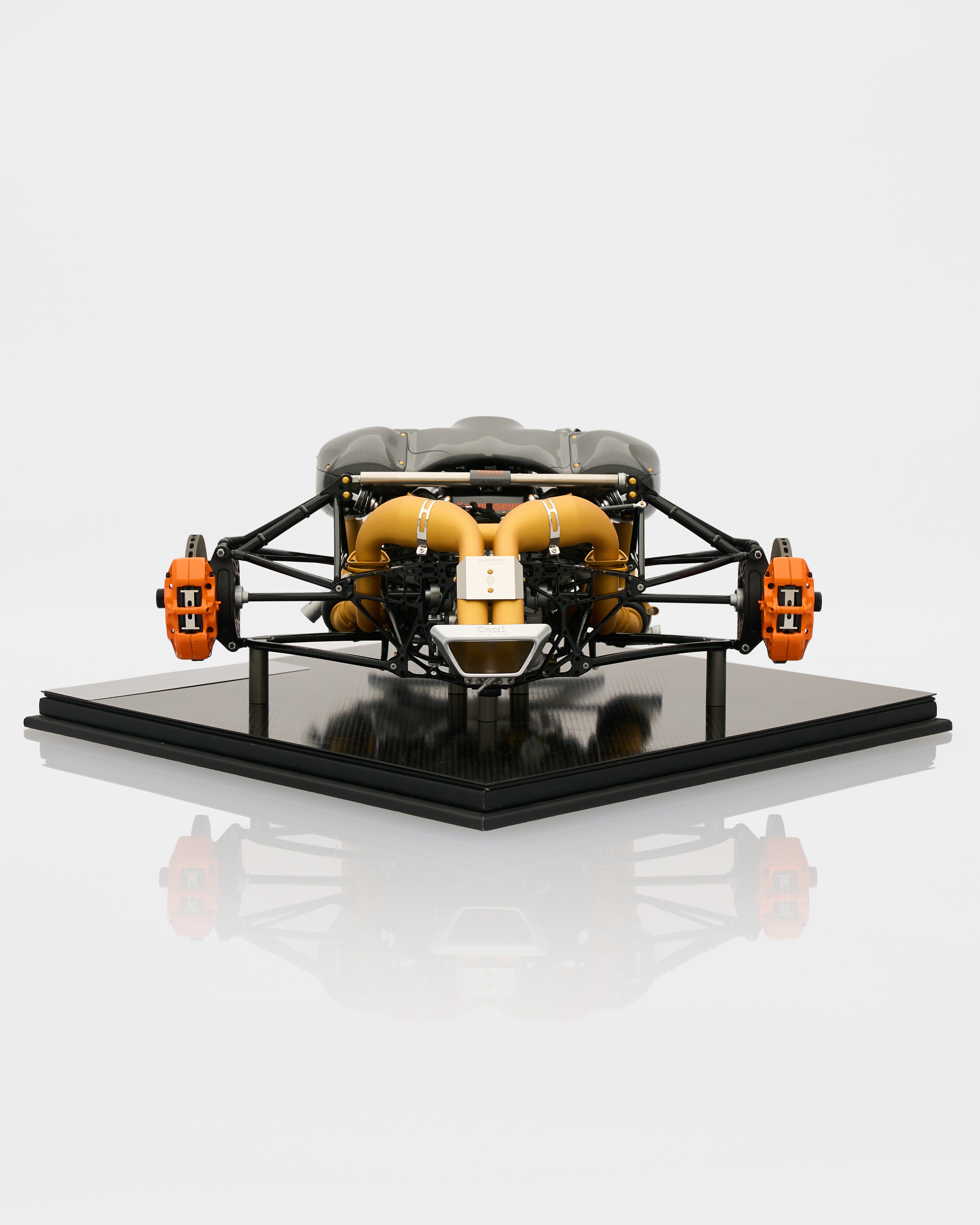 Model of a car engine on a reflective surface with a white background