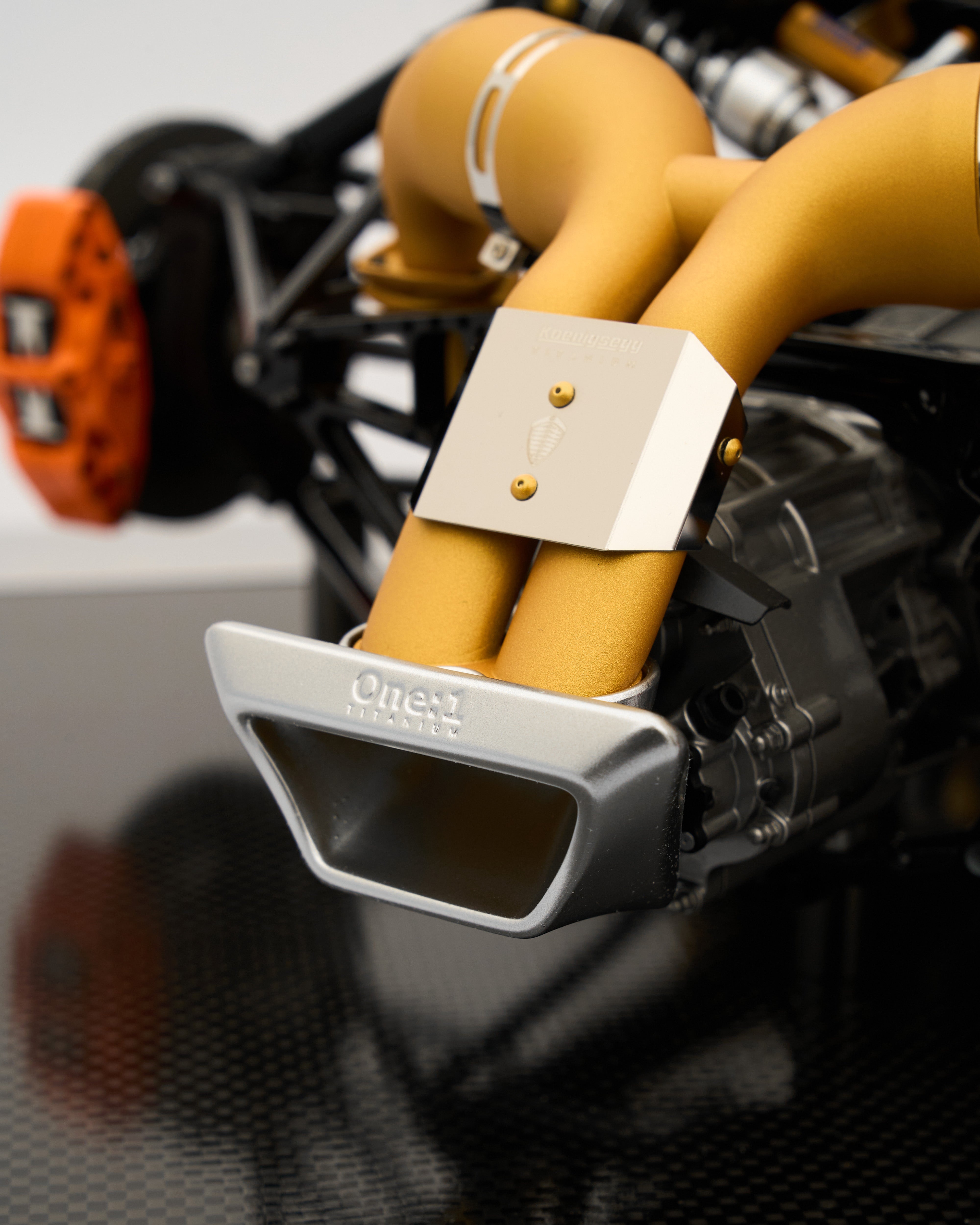 Close-up of a car exhaust with 'OneUp' branding on a blurred background