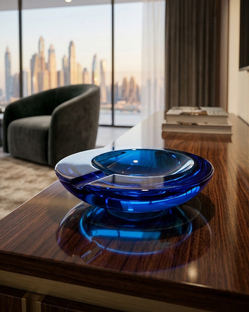Blue glass ashtray on a wooden surface with a cityscape view in the background