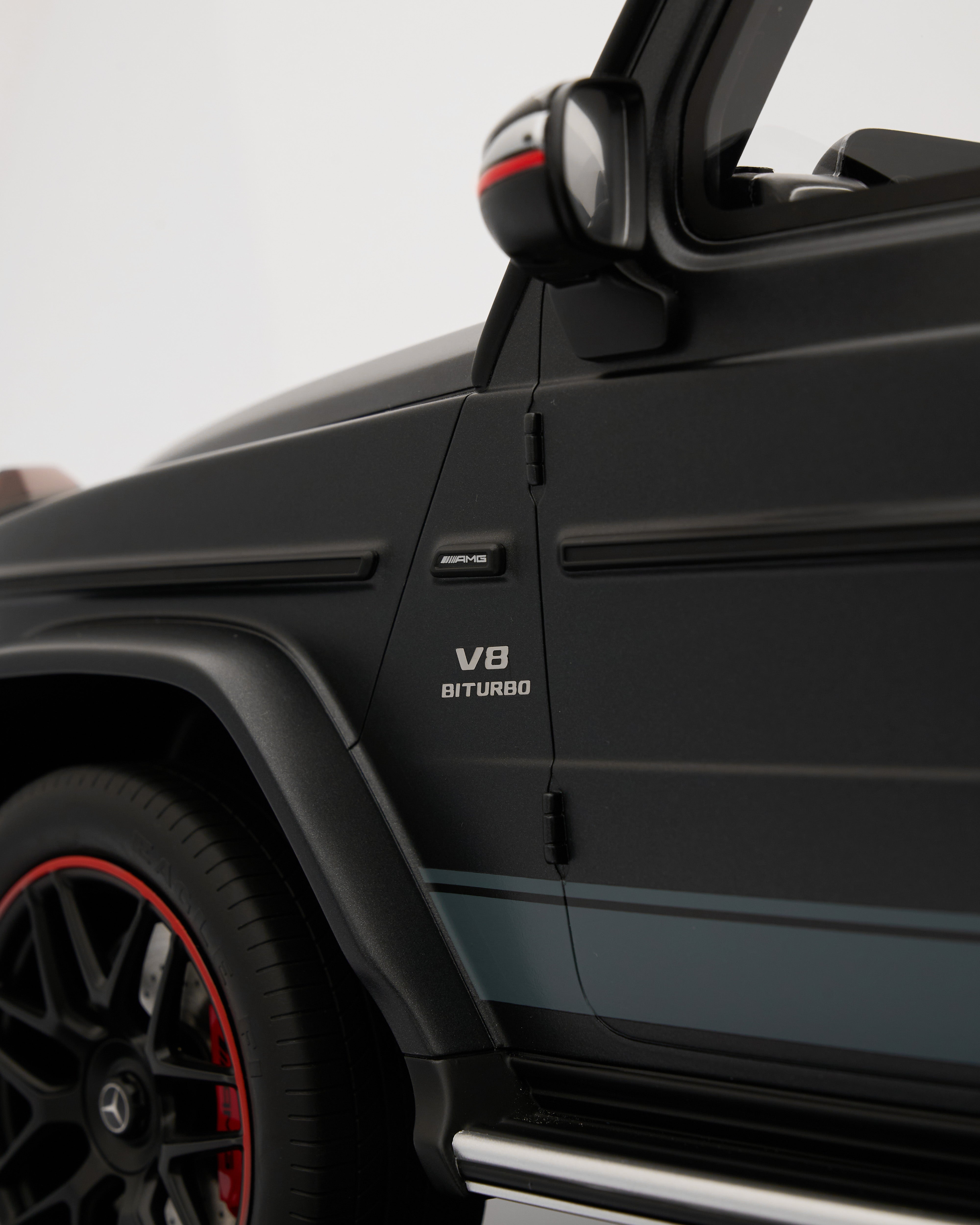 Close-up of a black Mercedes-Benz G-Class with 'V8 Biturbo' text on a gray background