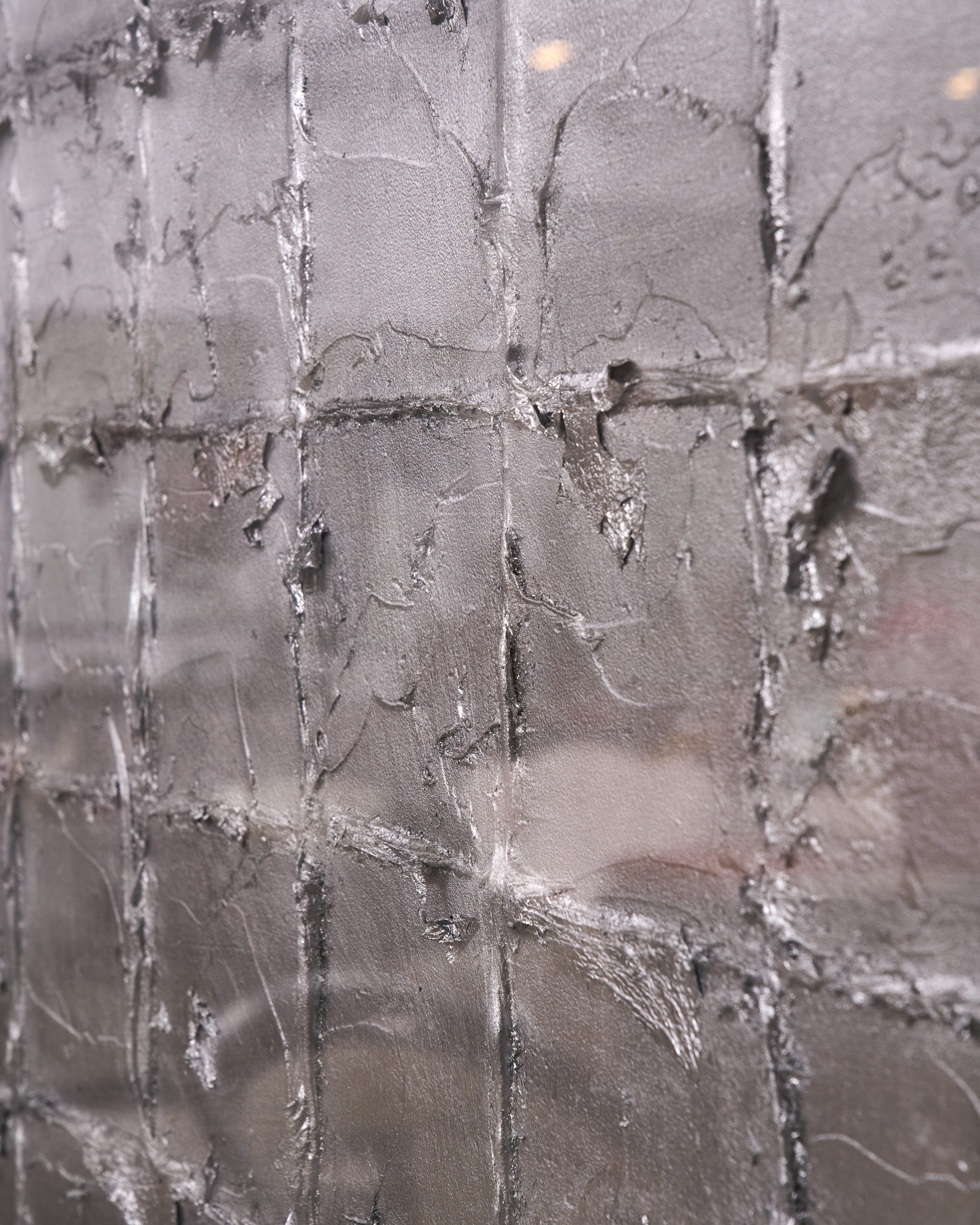 A close-up of a textured gray tiled surface with a grid pattern and distressed, weathered details.