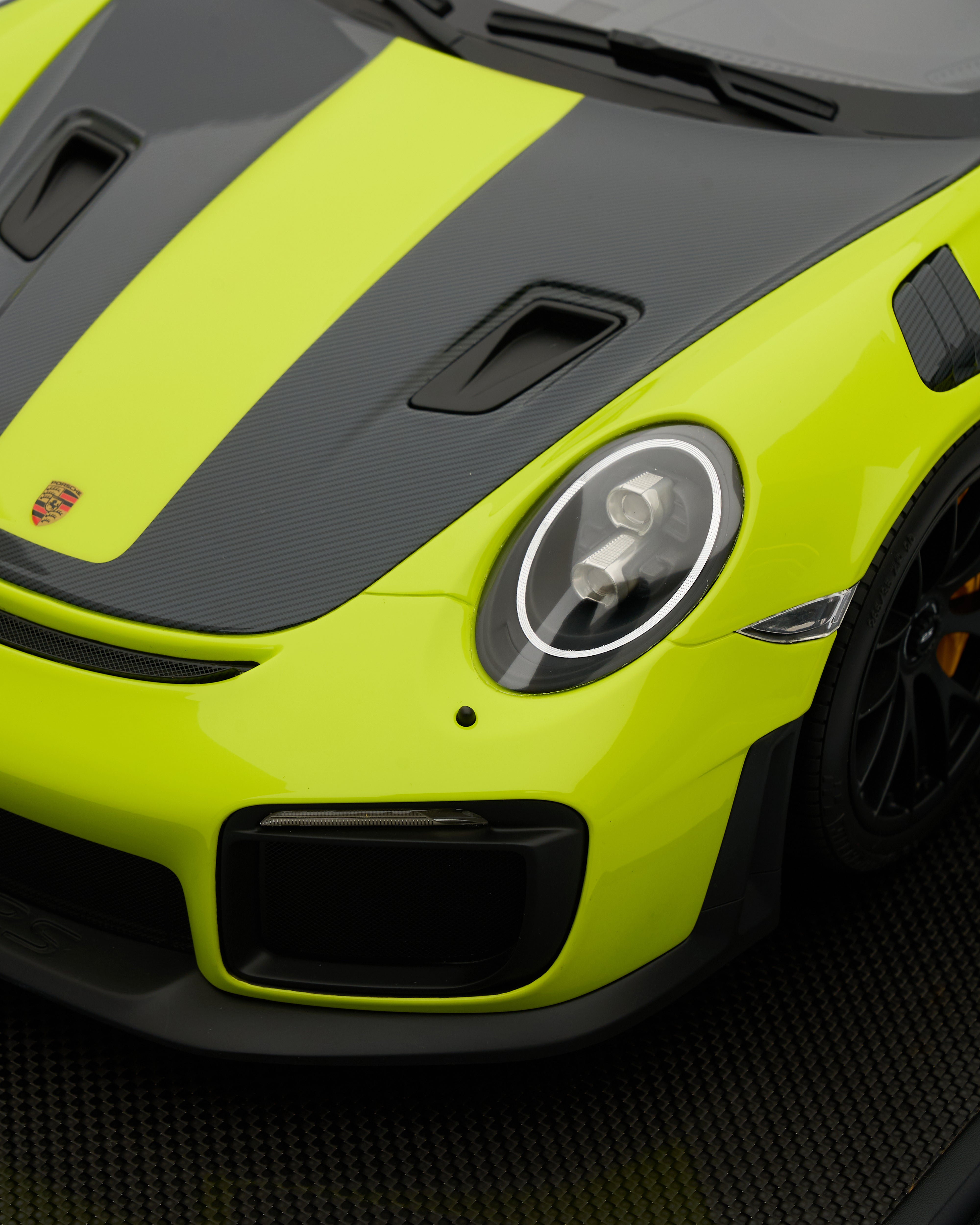 Close-up of a lime green and black sports car with a visible Porsche logo.