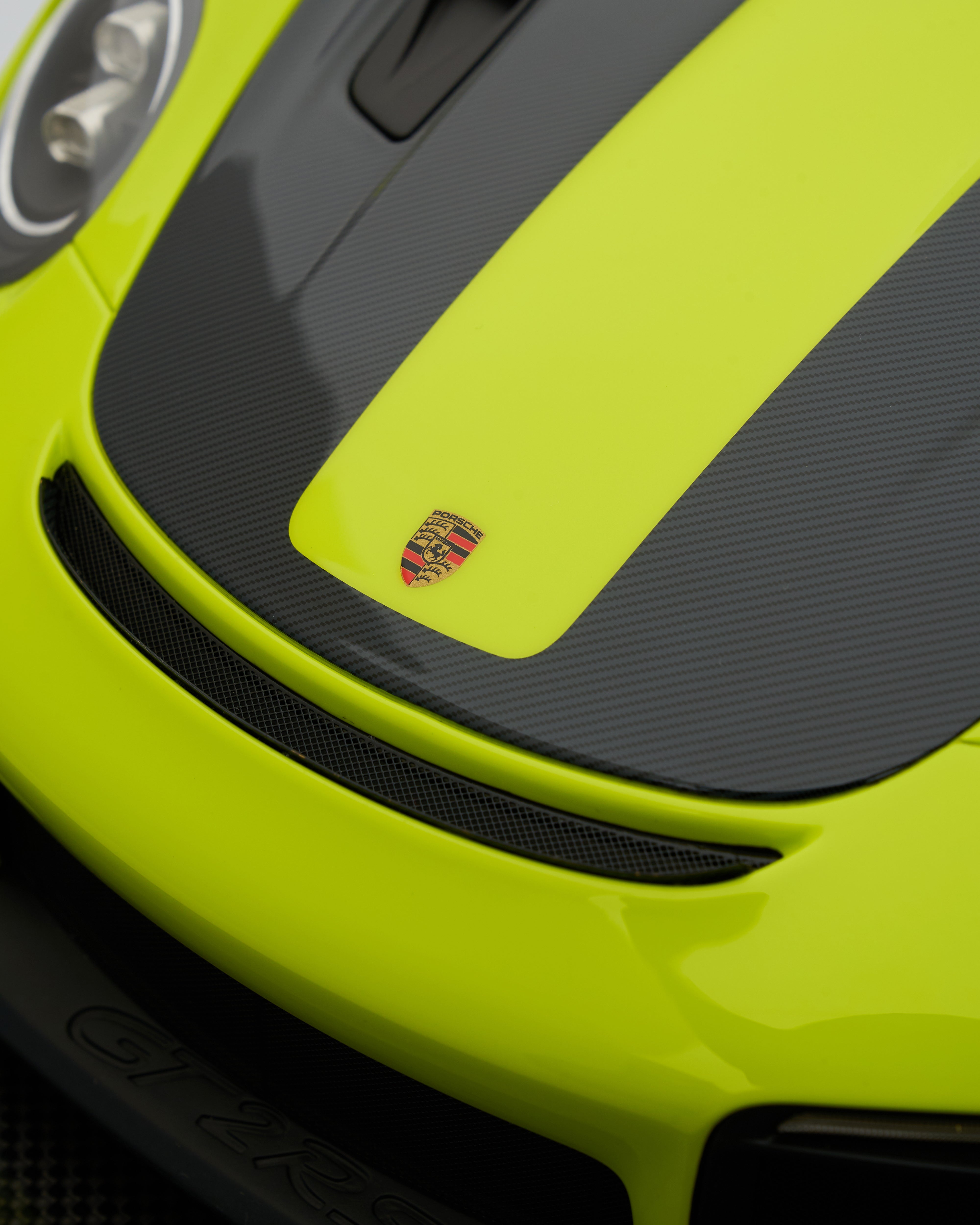 Close-up of a lime green and black car with a logo on the hood.