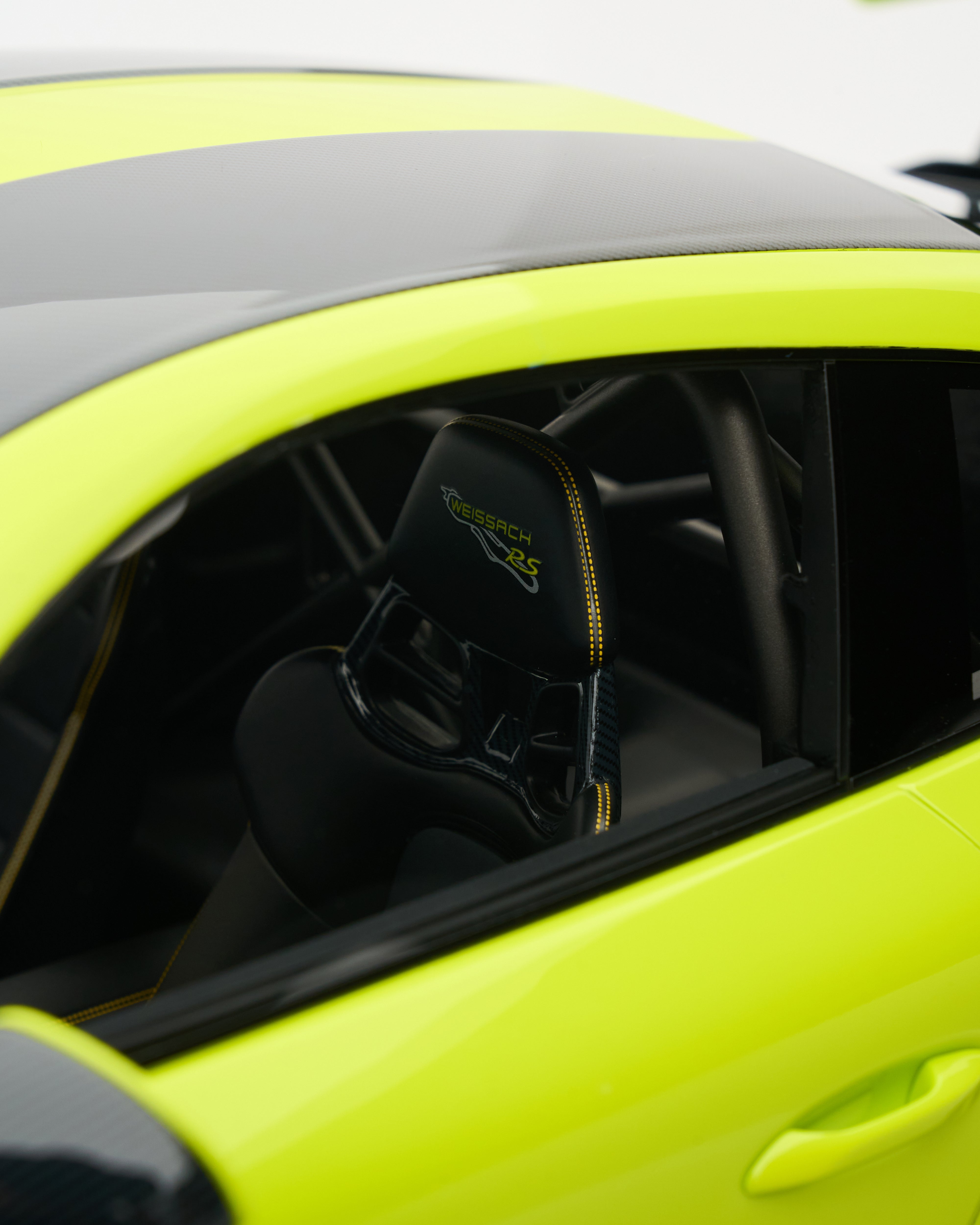Close-up of a car's open door with a black bag inside, on a bright yellow car.