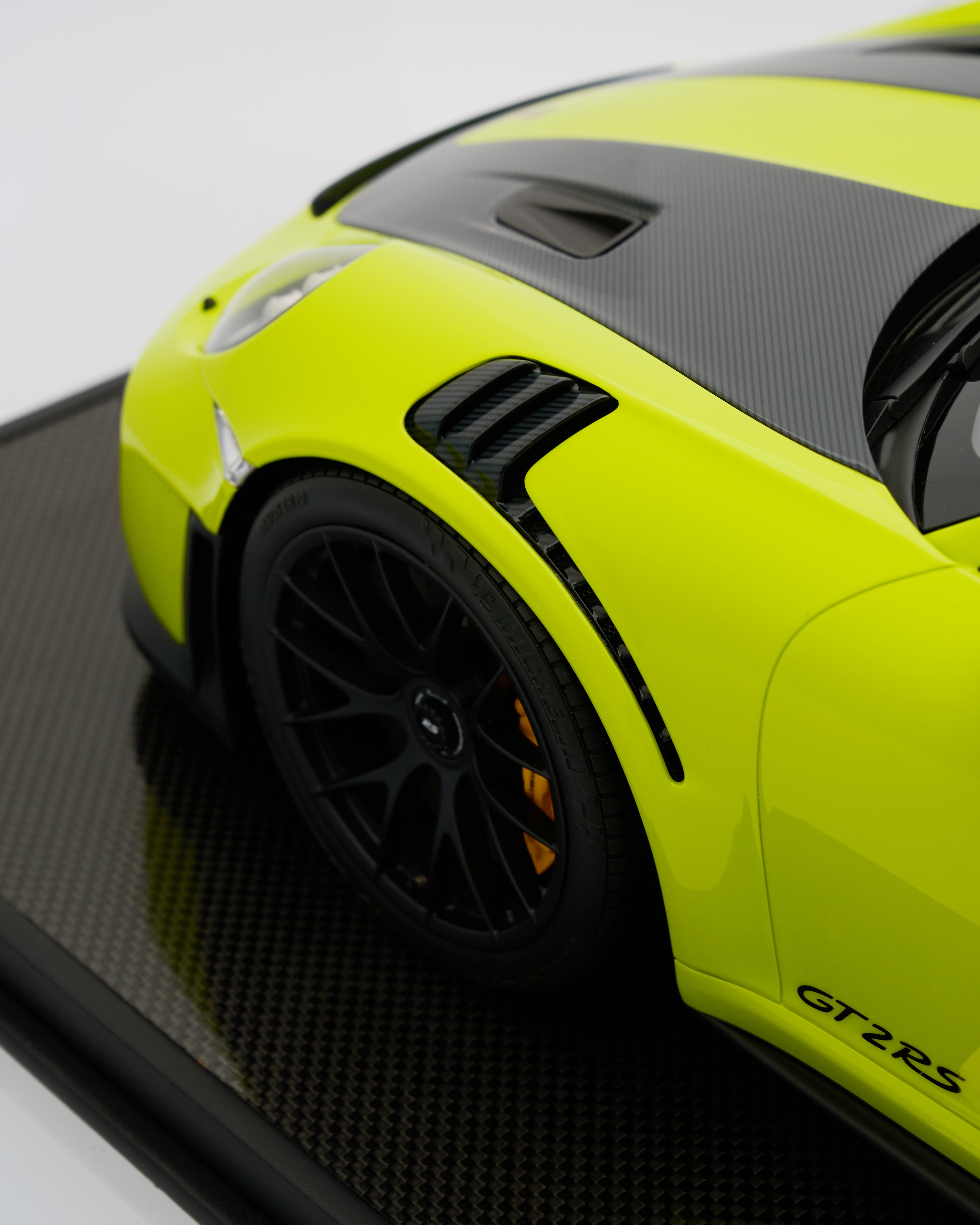 Close-up of a lime green sports car with black accents on a reflective surface.