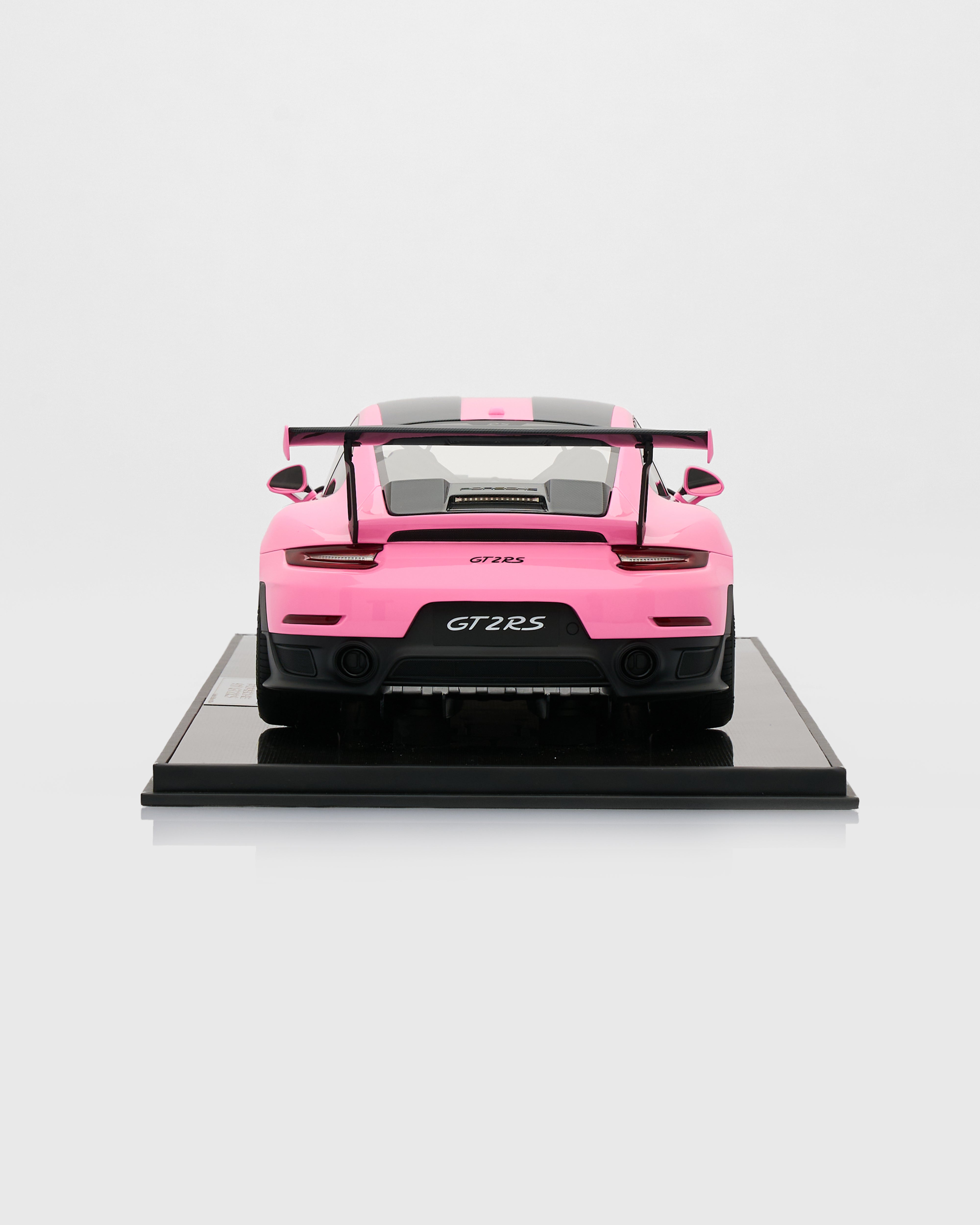 Pink model car on a black platform with a white background