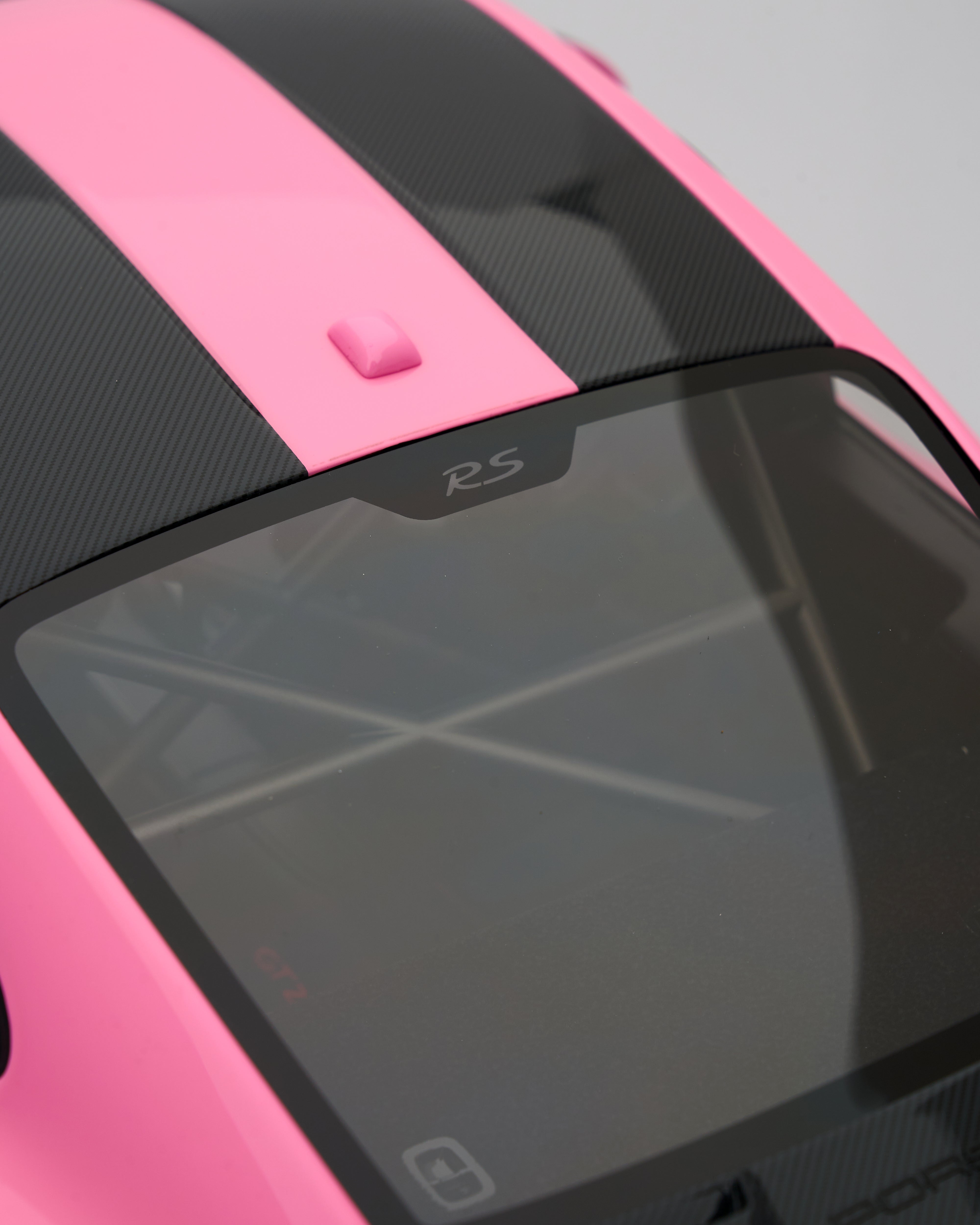 Close-up of a pink and black car with 'RS' branding on a gray background