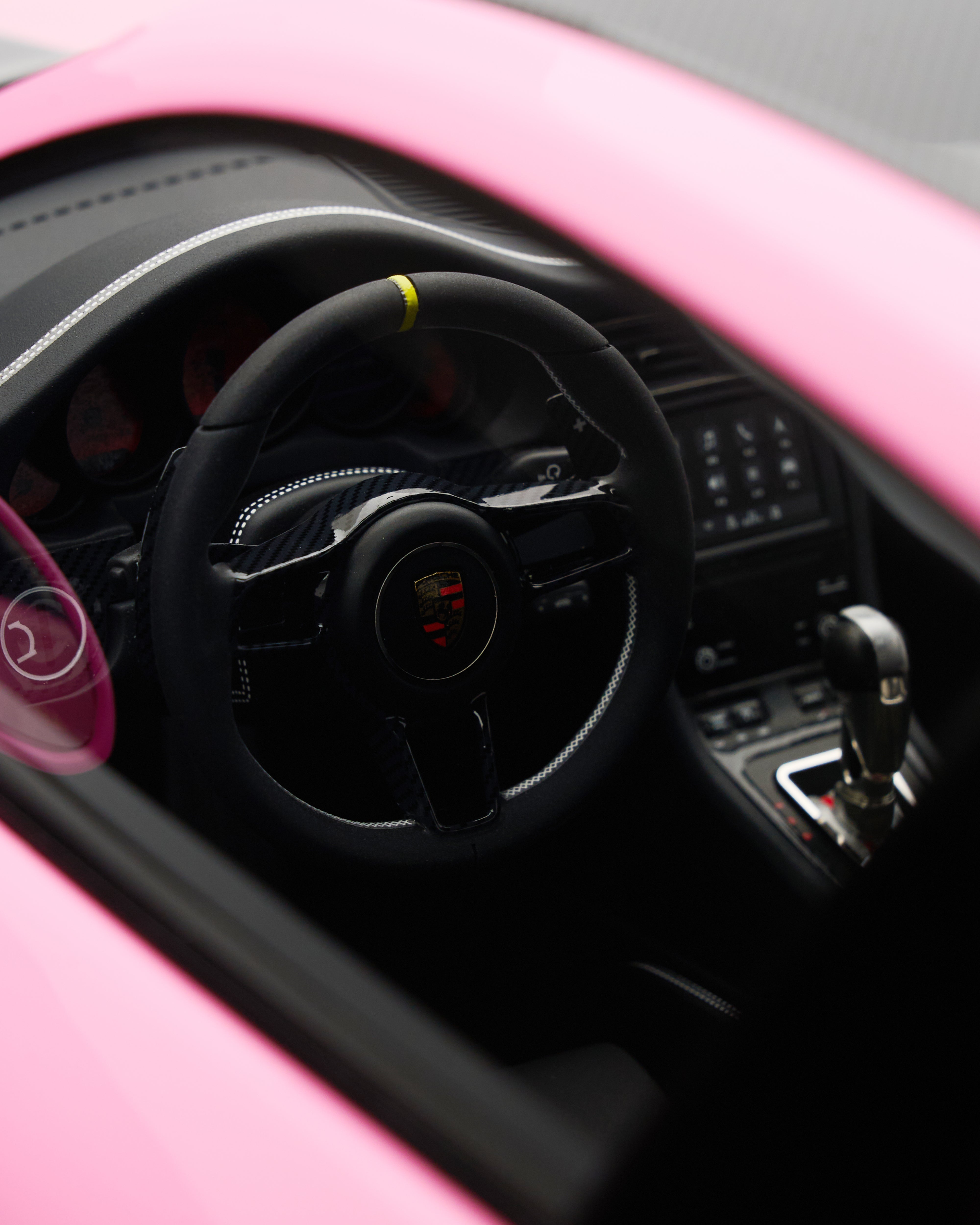 Close-up of a car's steering wheel and dashboard with a pink exterior.
