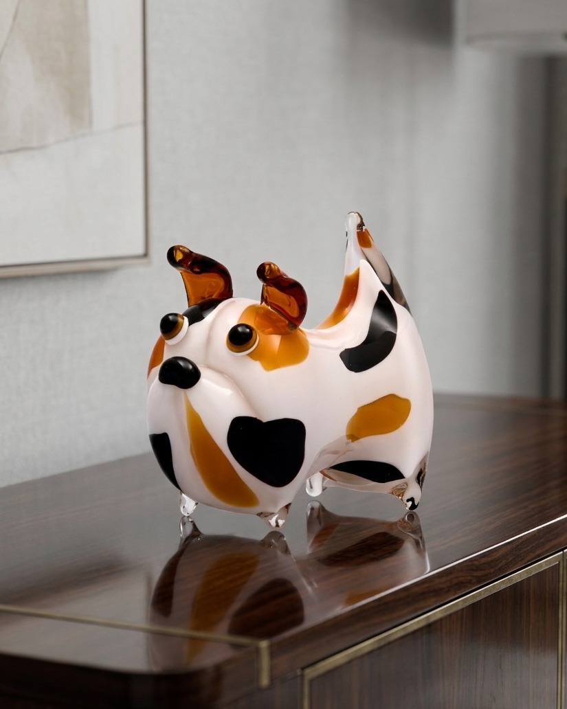 Decorative dog figurine with black, brown, and white pattern on a reflective surface.