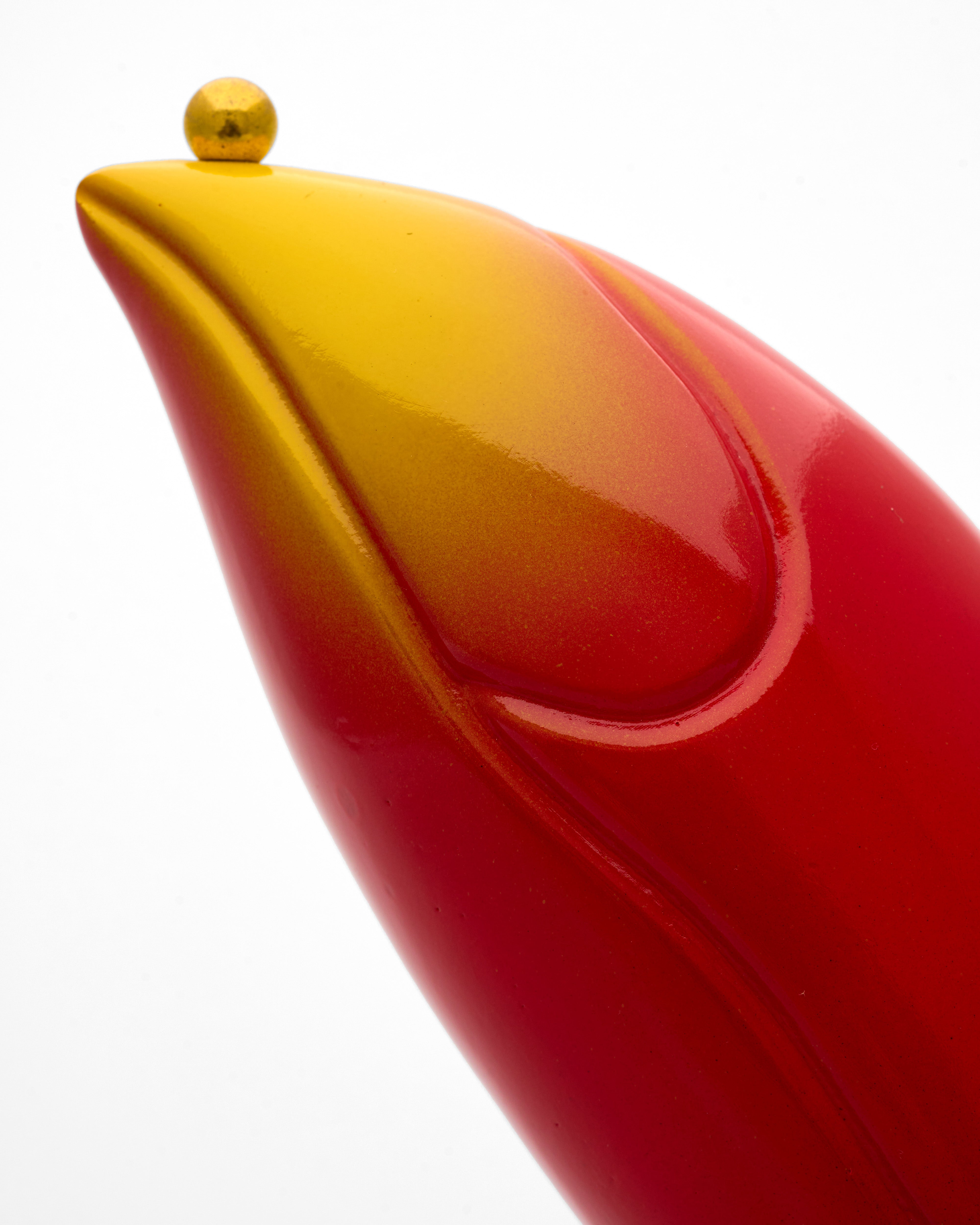 Close-up of a red and yellow object with a gold top on a white background