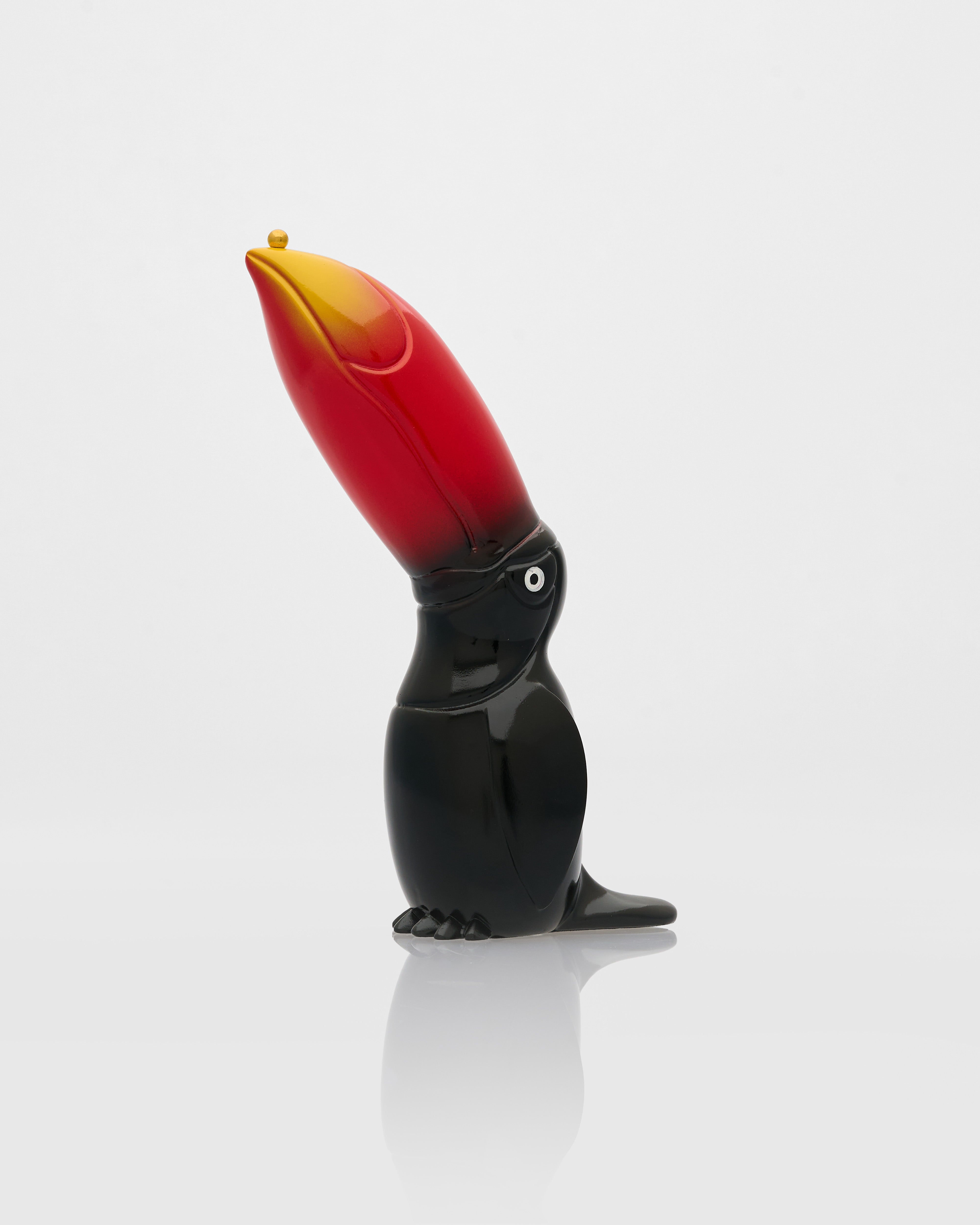 Glass sculpture of a toucan with a red beak on a white background