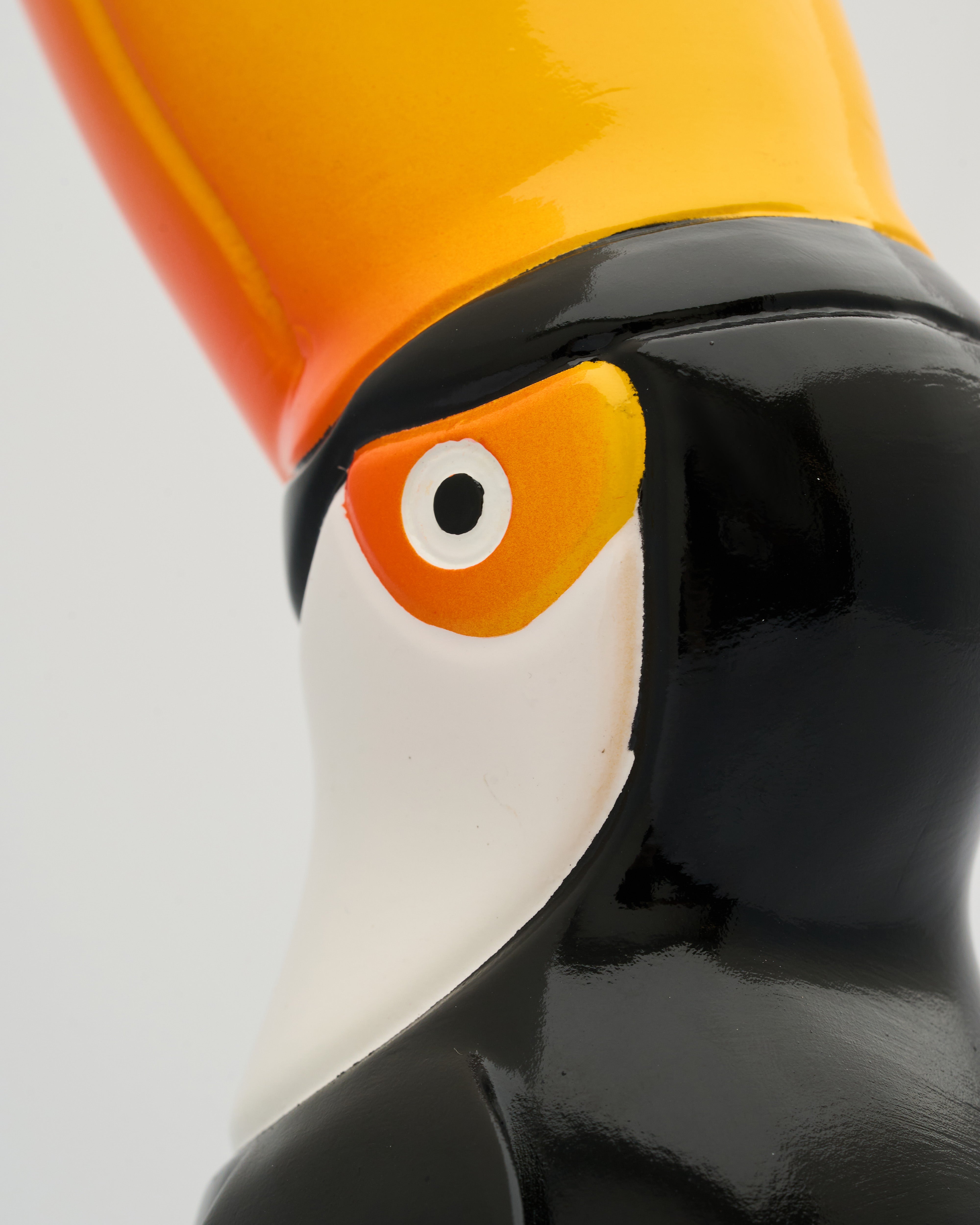 Close-up of a glass toucan figurine with a yellow and orange beak on a white background