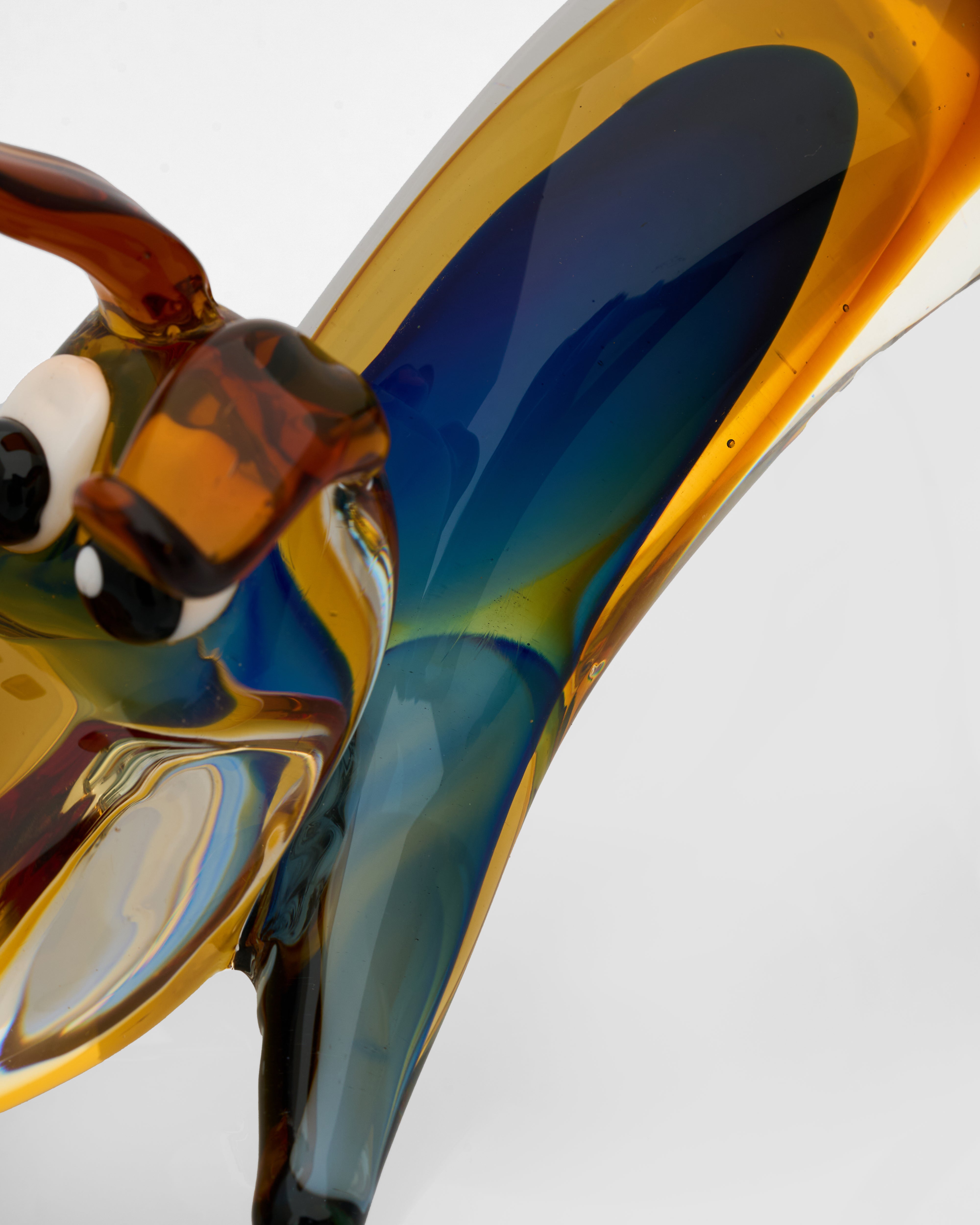 Close-up of a colorful glass sculpture with animal-like features on a white background