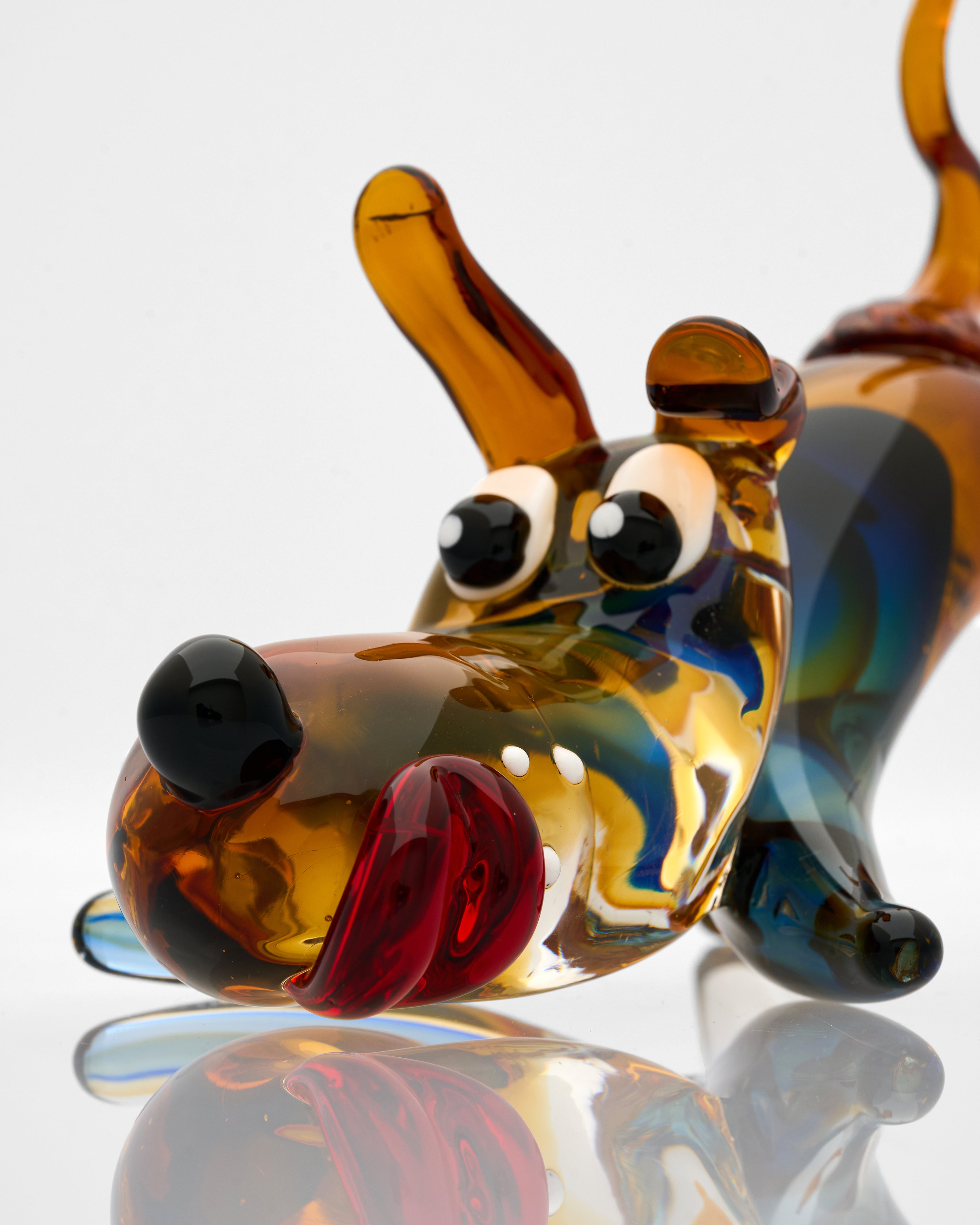 Colorful glass dog figurine on a reflective surface with a white background