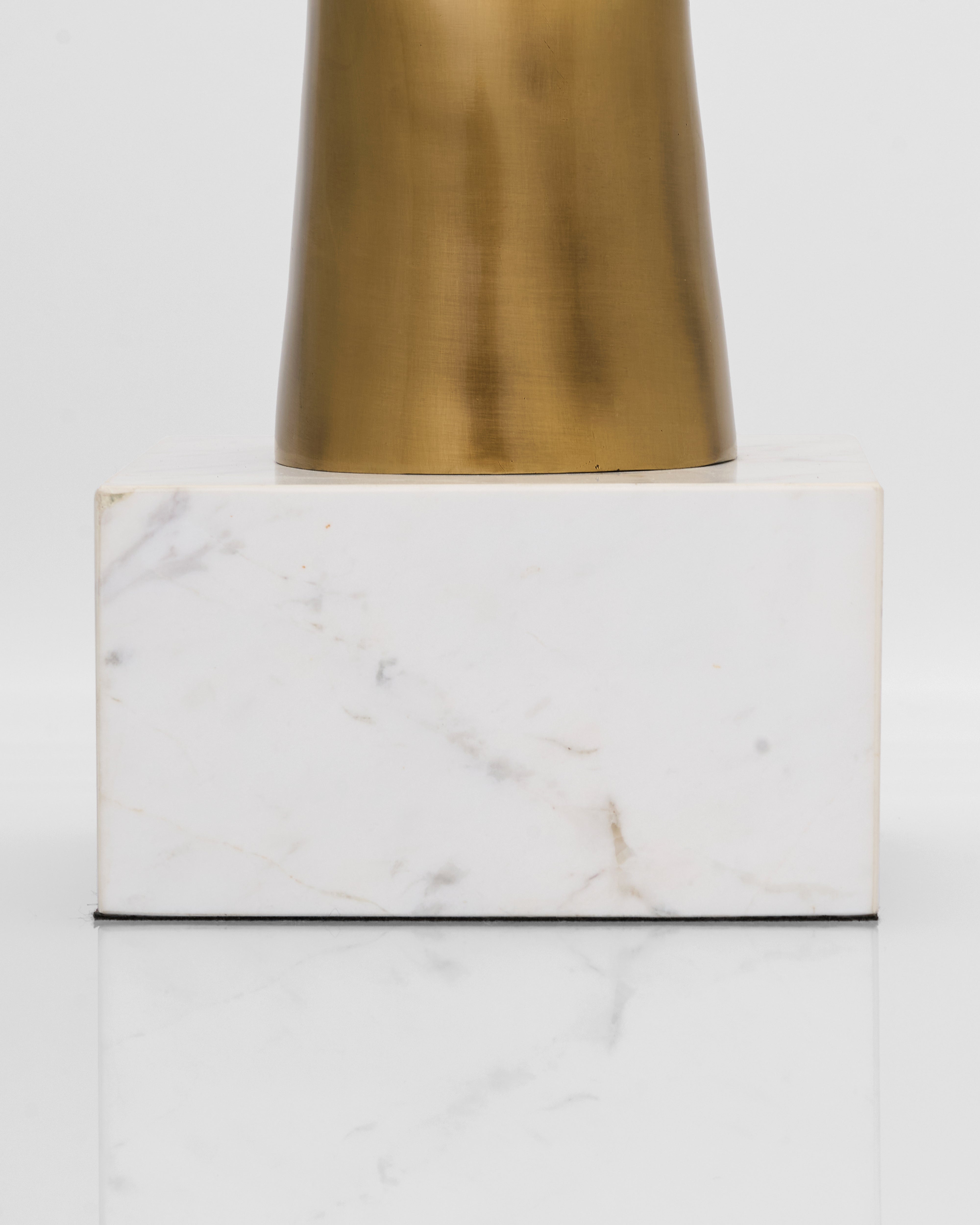 Brass lampshade on a marble base with a white background