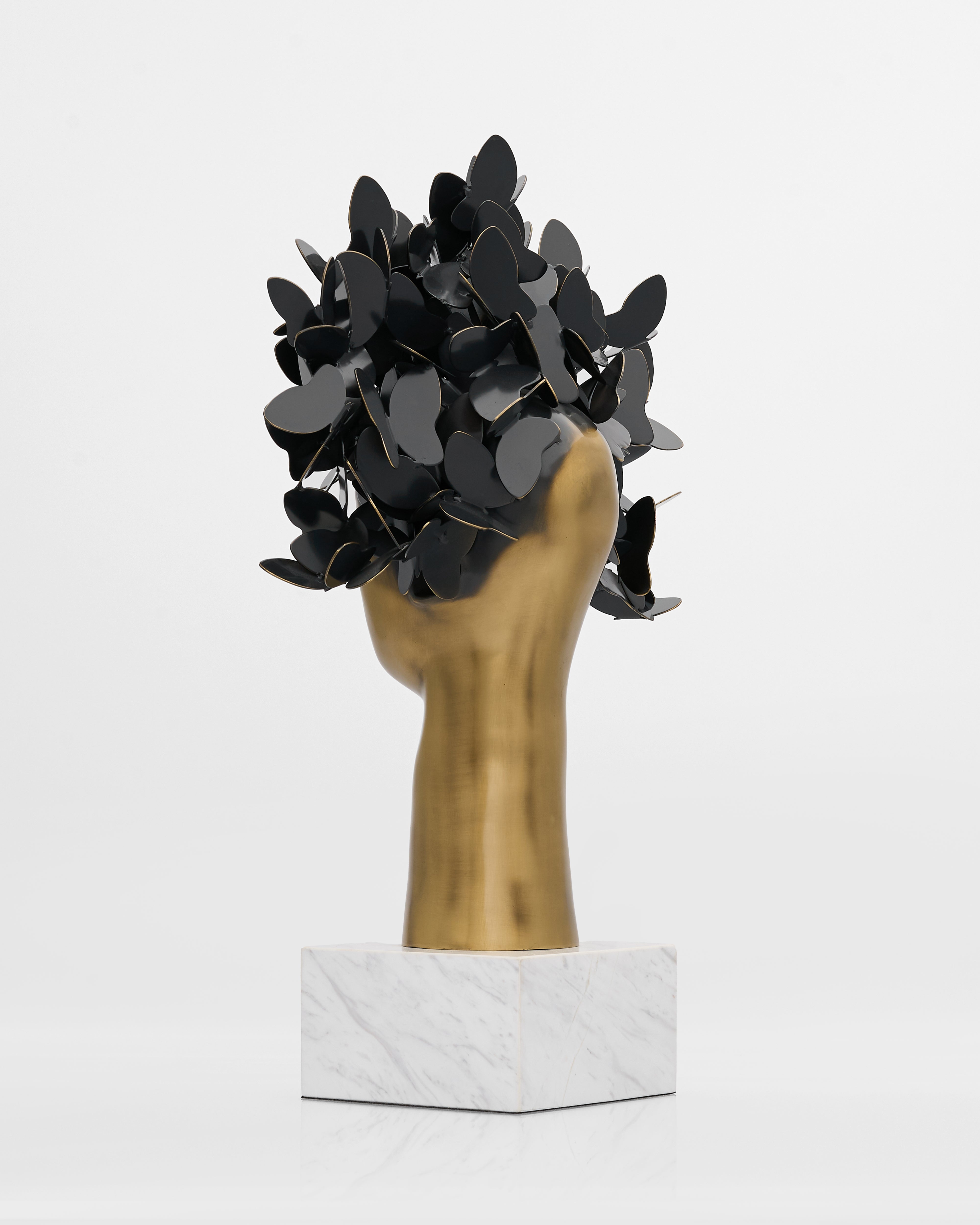 Decorative headpiece with black leaves on a gold head and marble base against a white background