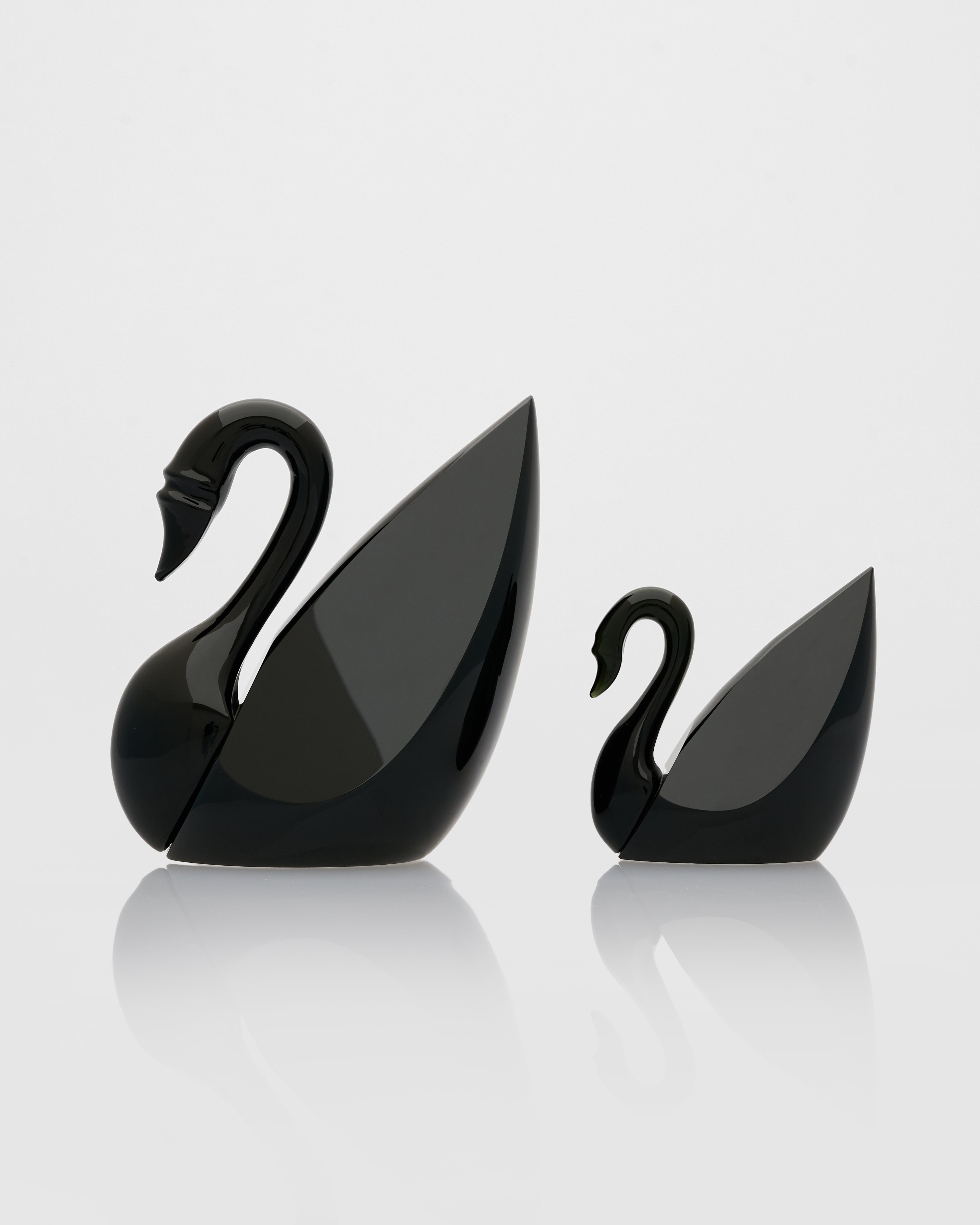 Two black swan-shaped objects on a white background