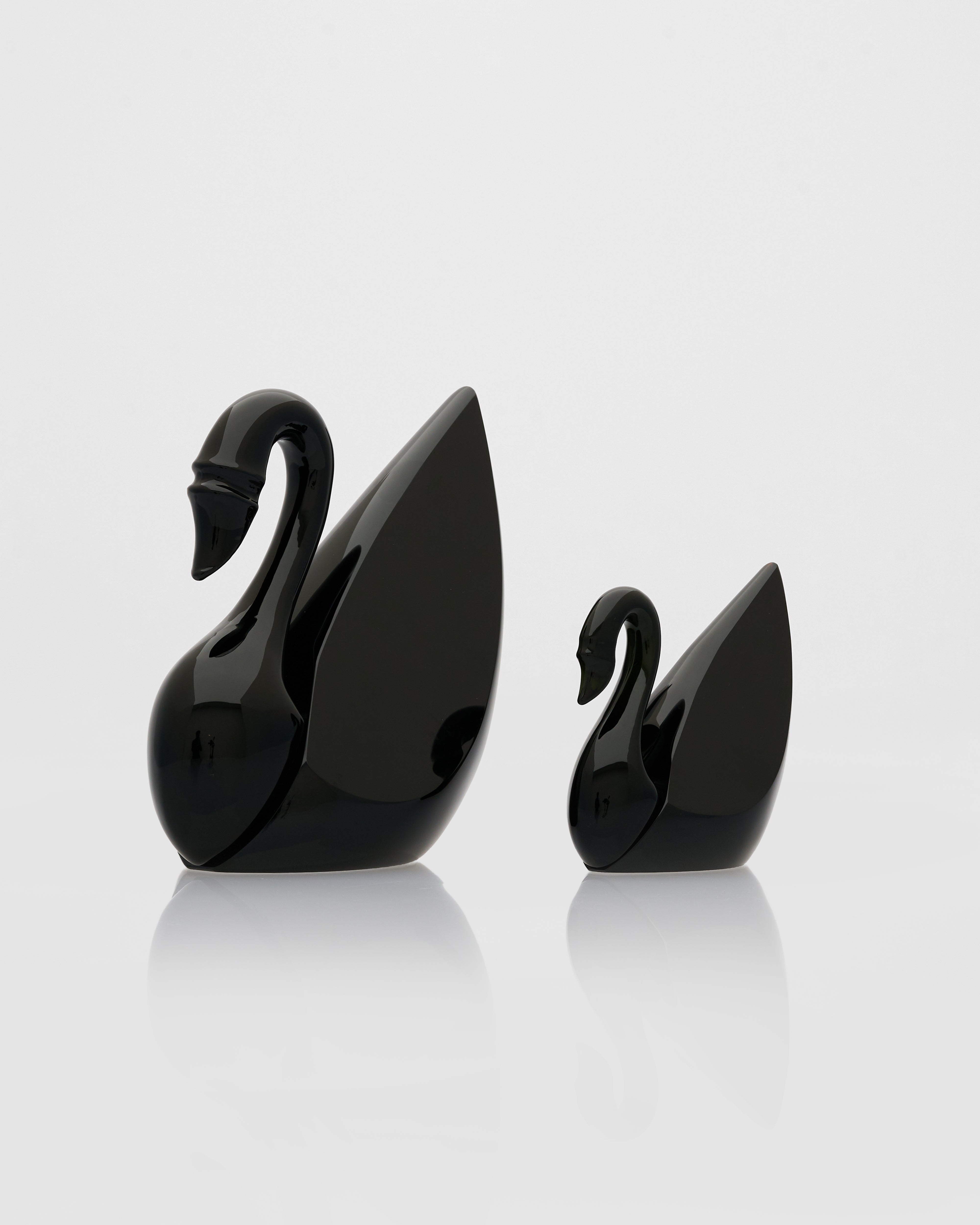 Two black swan-shaped objects on a white background