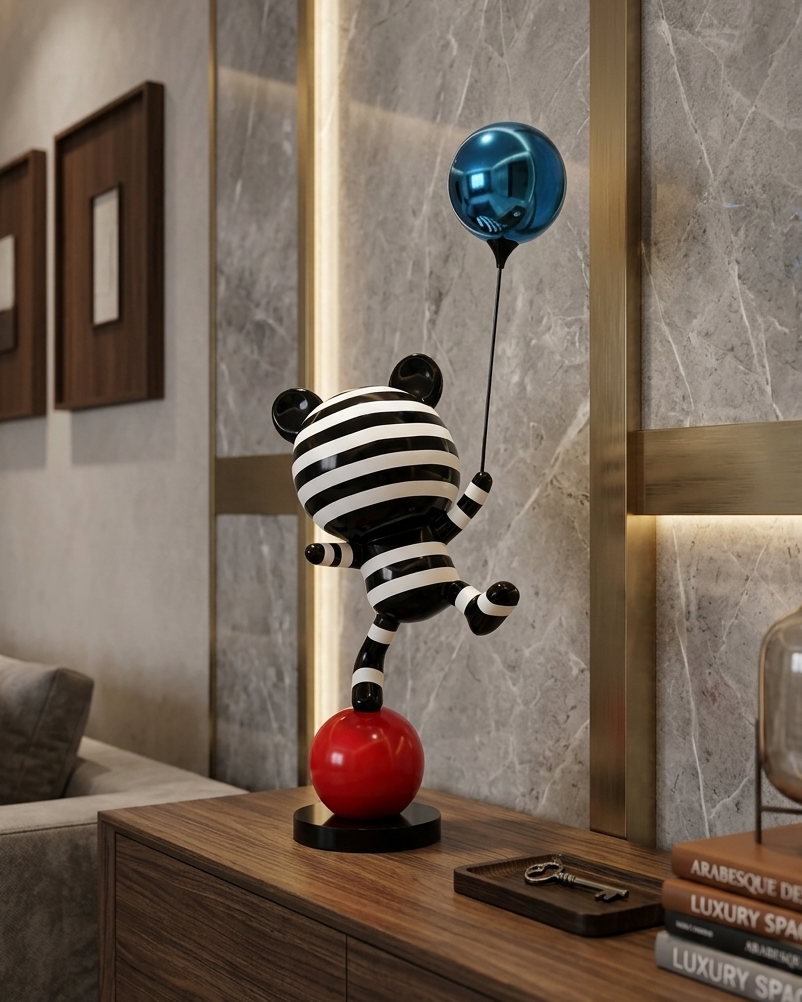 Decorative sculpture of a black and white striped animal with a blue balloon on a wooden table.